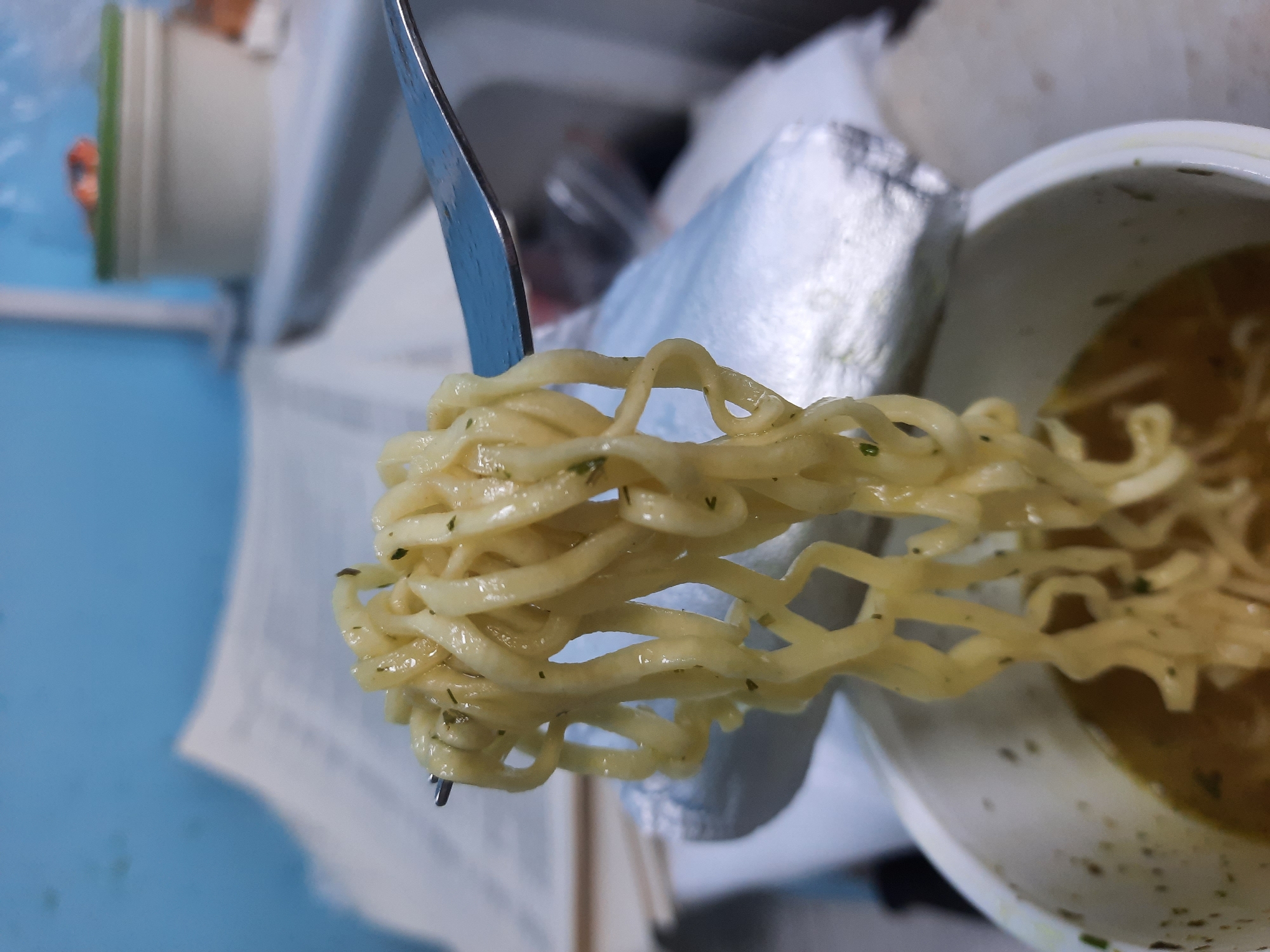 Person eats noodles in cluttered Krasnogorskoye storage area