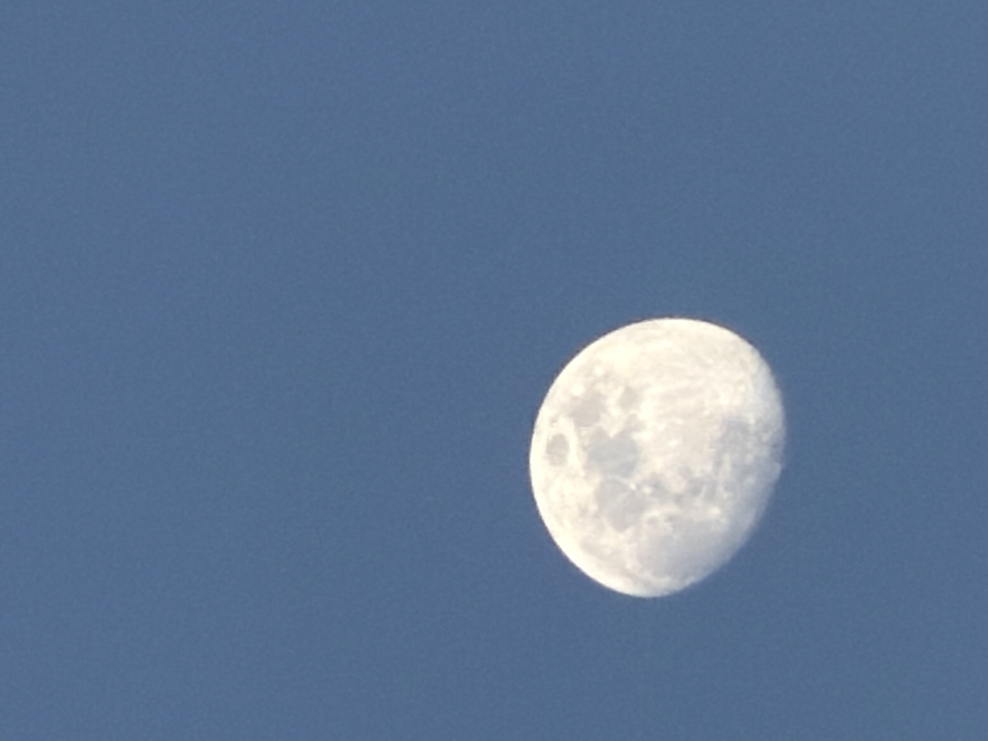 Half moon photographed against blue daytime sky in Milan