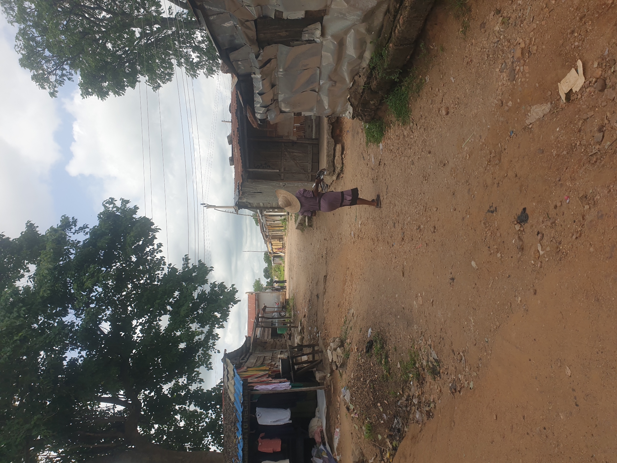Person with bicycle walks dirt road in developing area