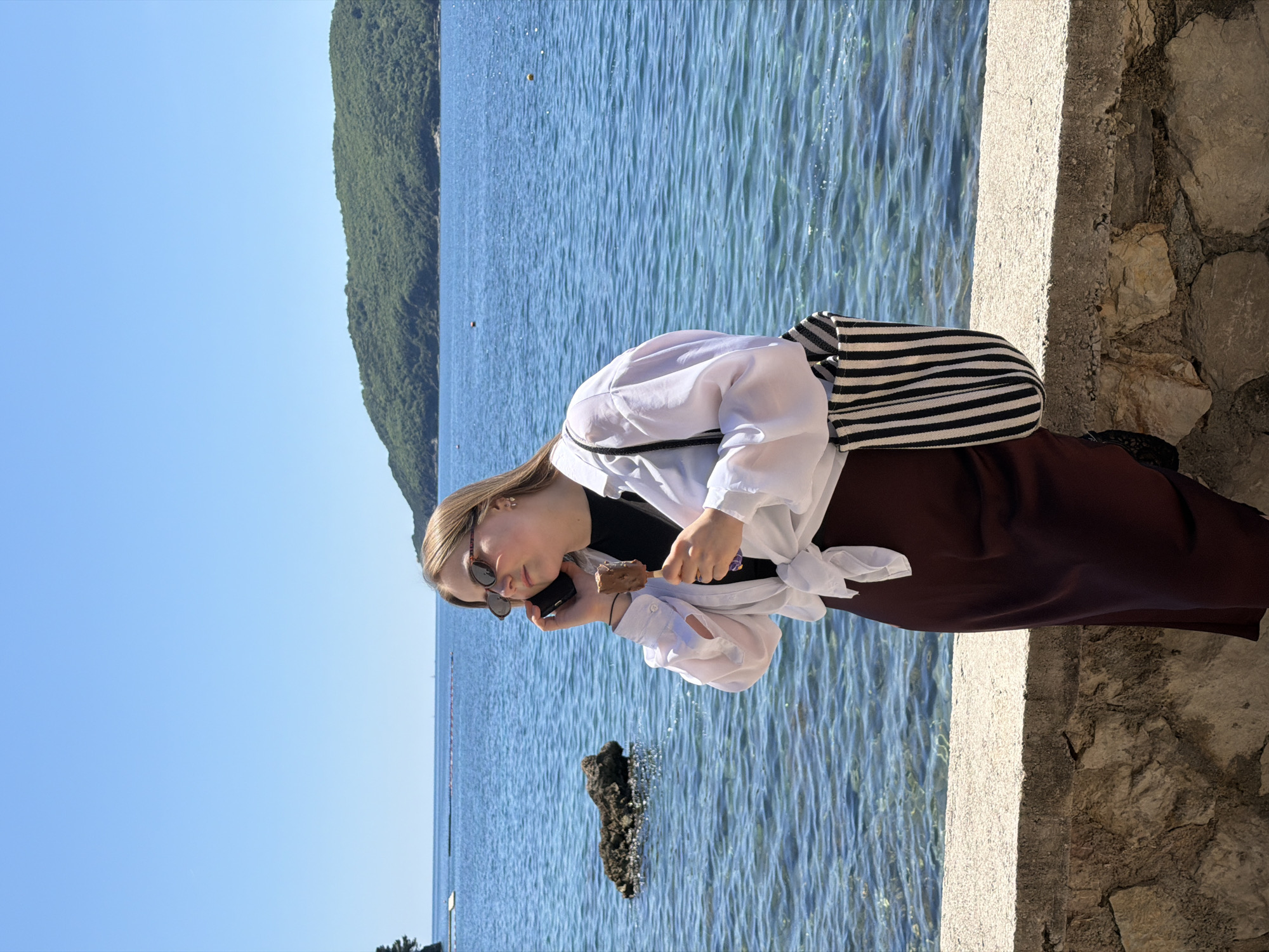 Woman enjoys phone call, ice cream at Budva seaside
