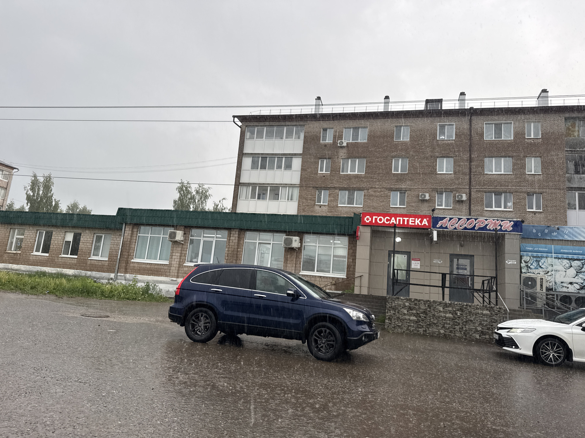 Heavy rainfall documented across Mozhga streets, vehicles navigate wet conditions