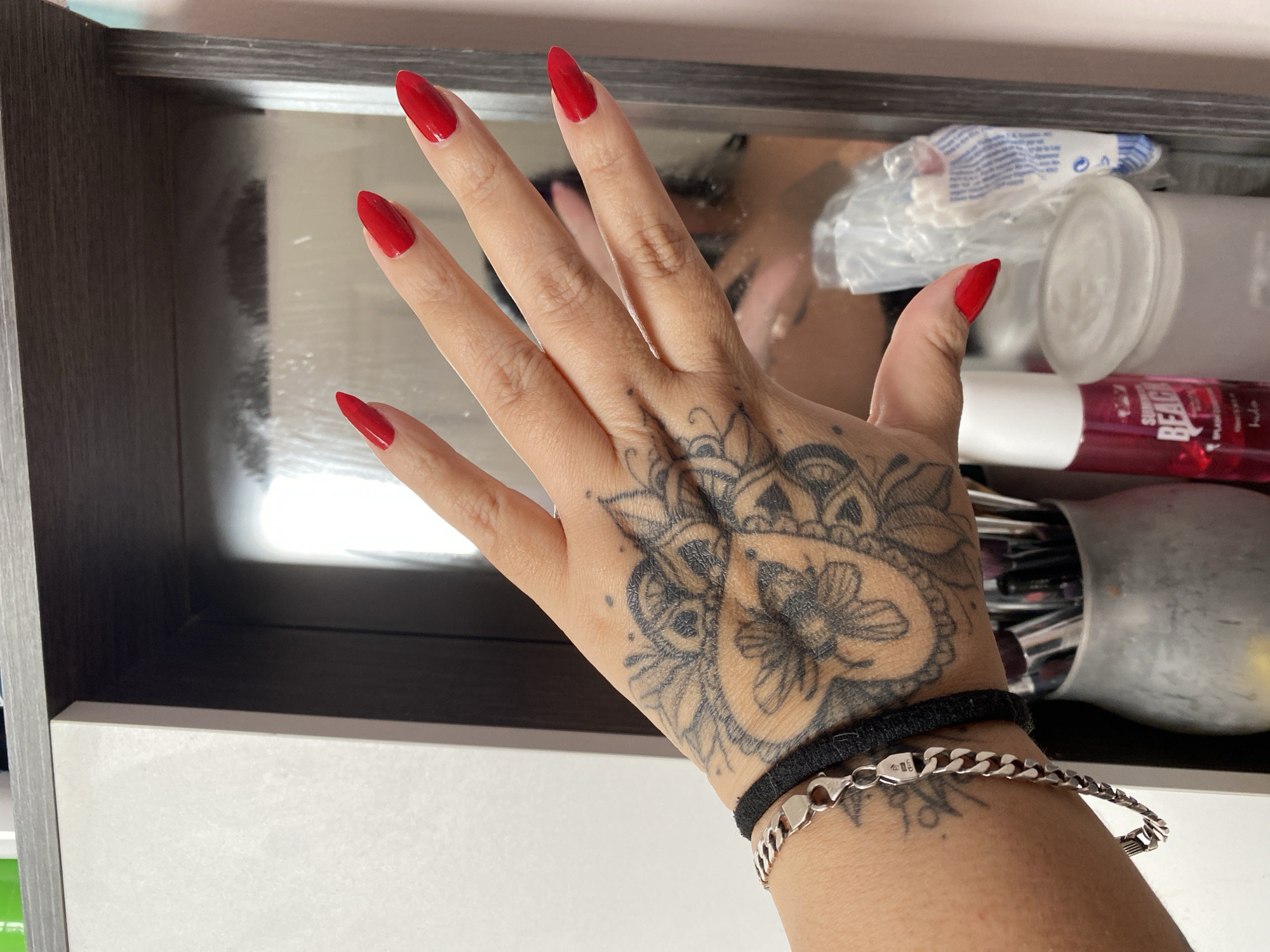 Hand with red nails and black tattoo photographed in Quito
