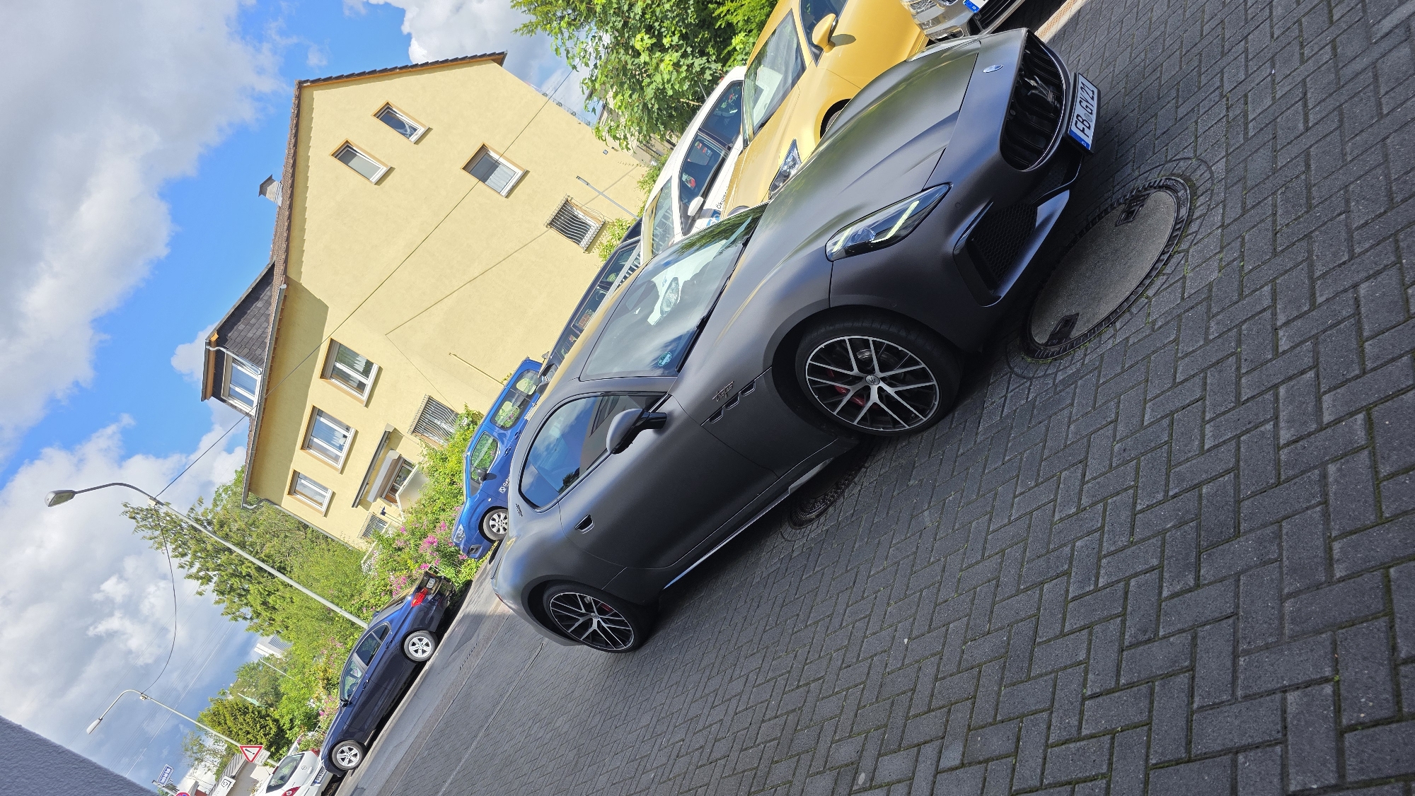 Luxury car gathering observed in urban brick-paved area