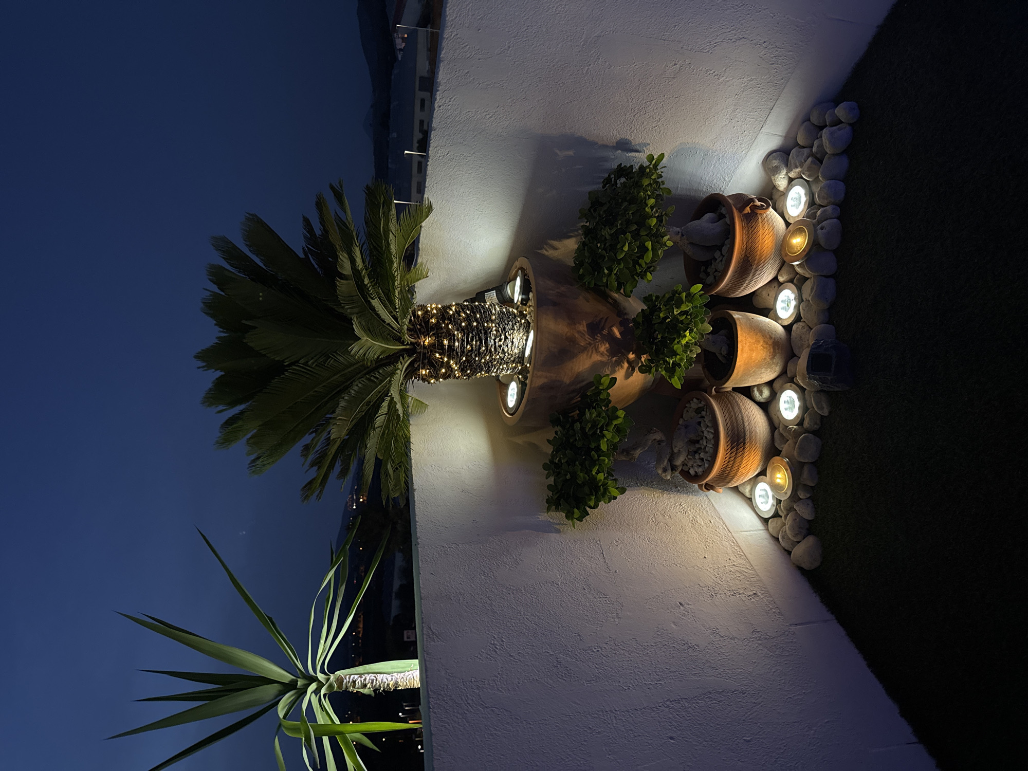 Vallada patio lights up at dusk around a jacuzzi and garden seating