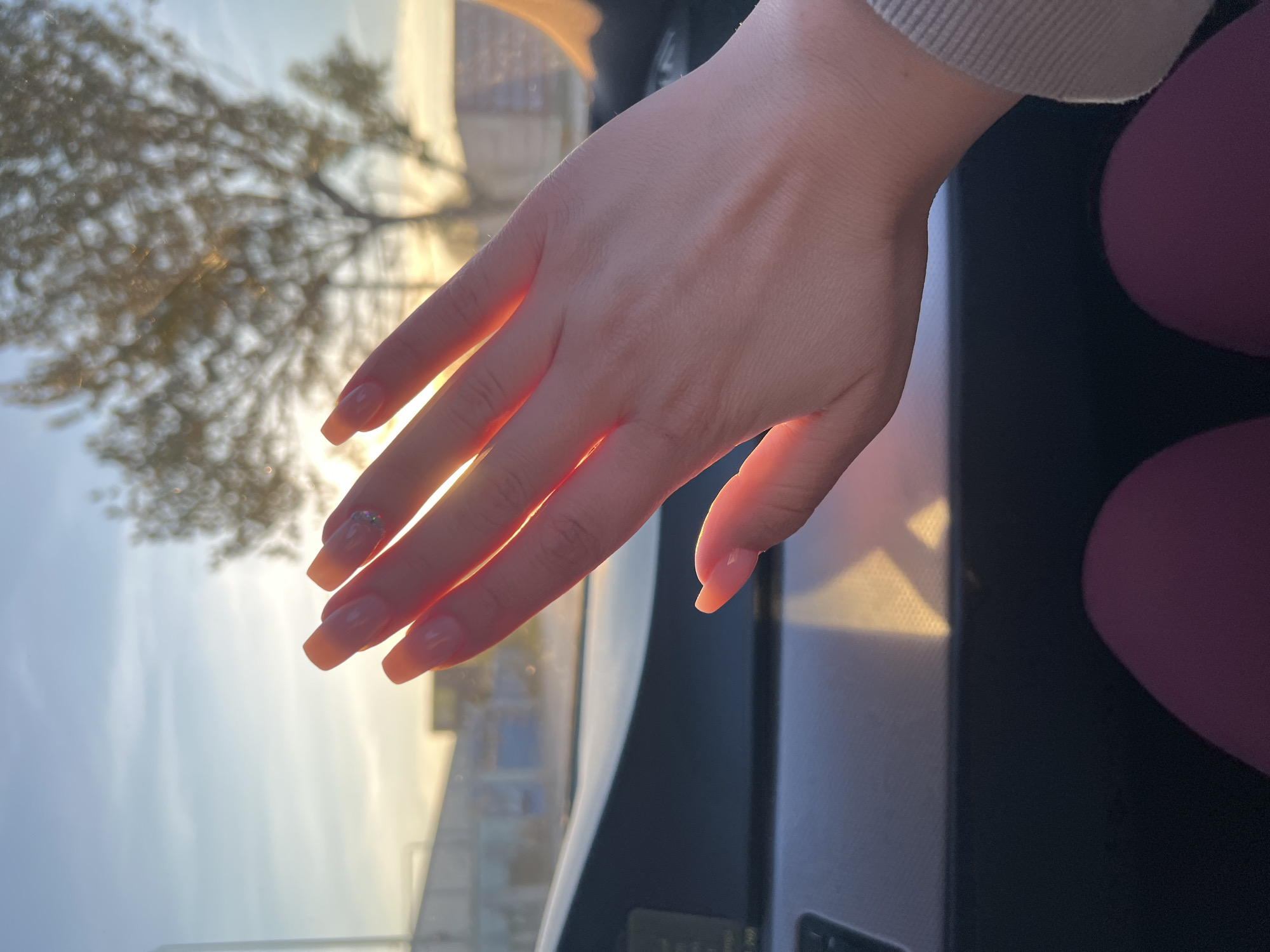 Person photographs manicured hands in golden sunlight, Plovdiv