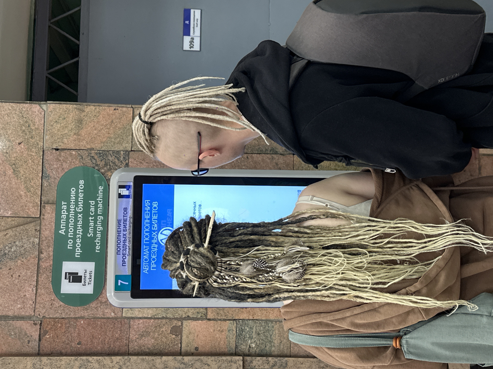 Buying tickets at a Saint Petersburg machine, dreadlocks in frame.