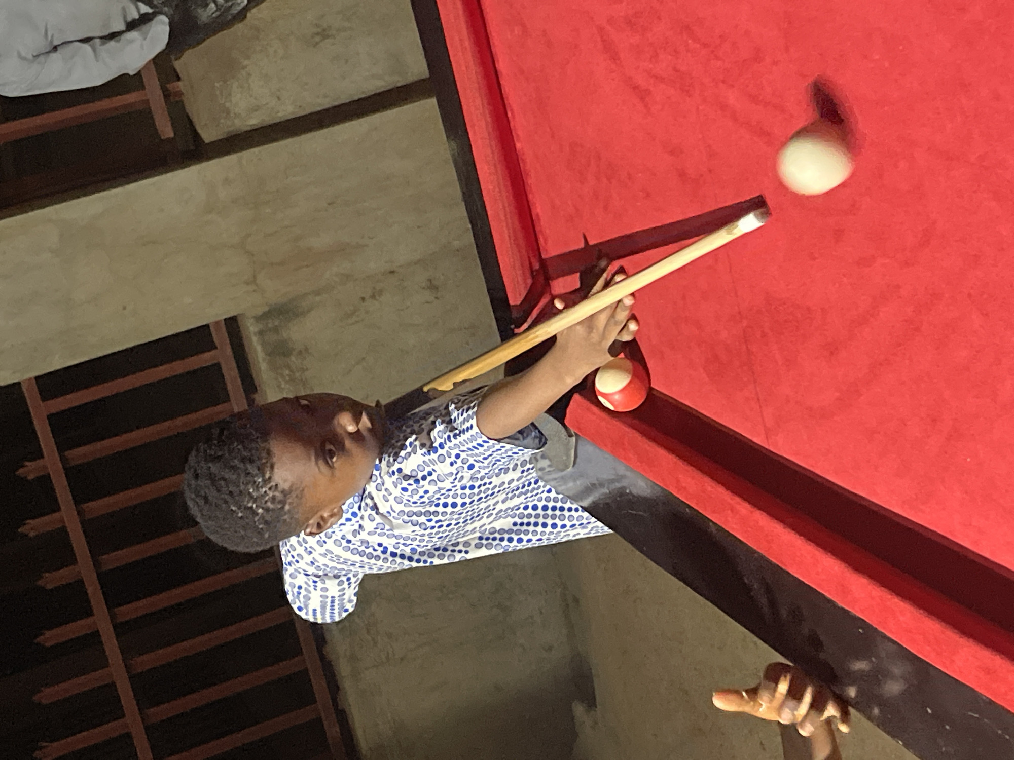 Boy plays outdoor billiards in Unguwar Gabas, Nigeria