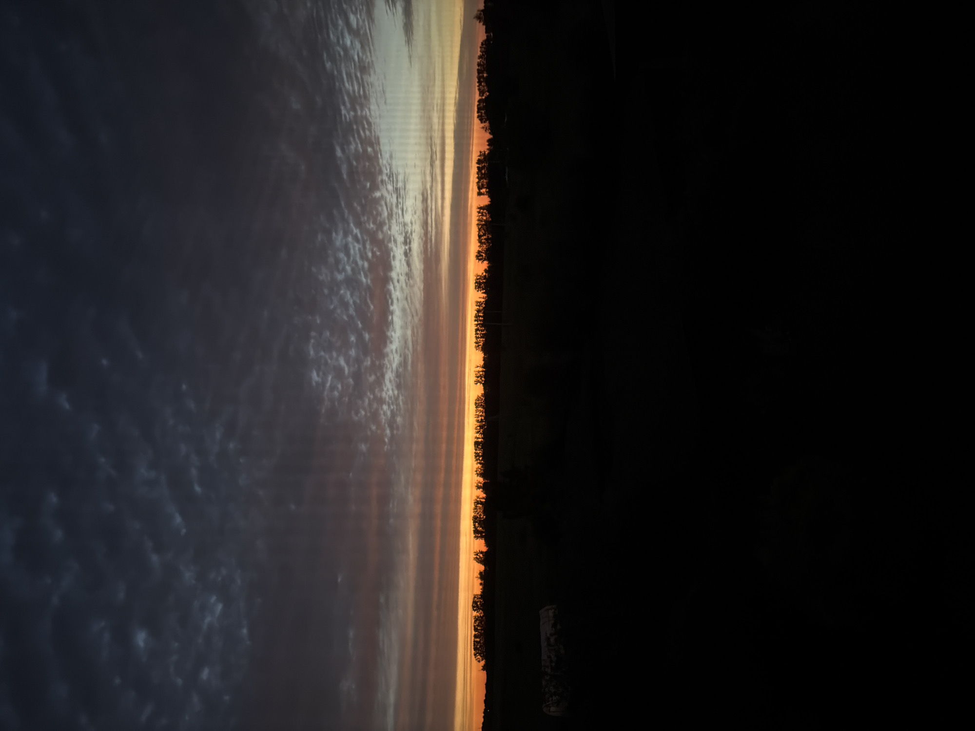 Orange glow and cloud-heavy sky over a Russian treeline