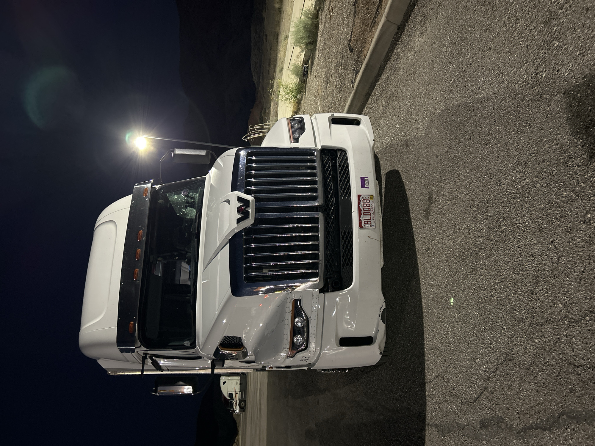 Late-night roadside wrench work on a parked semi in Salina