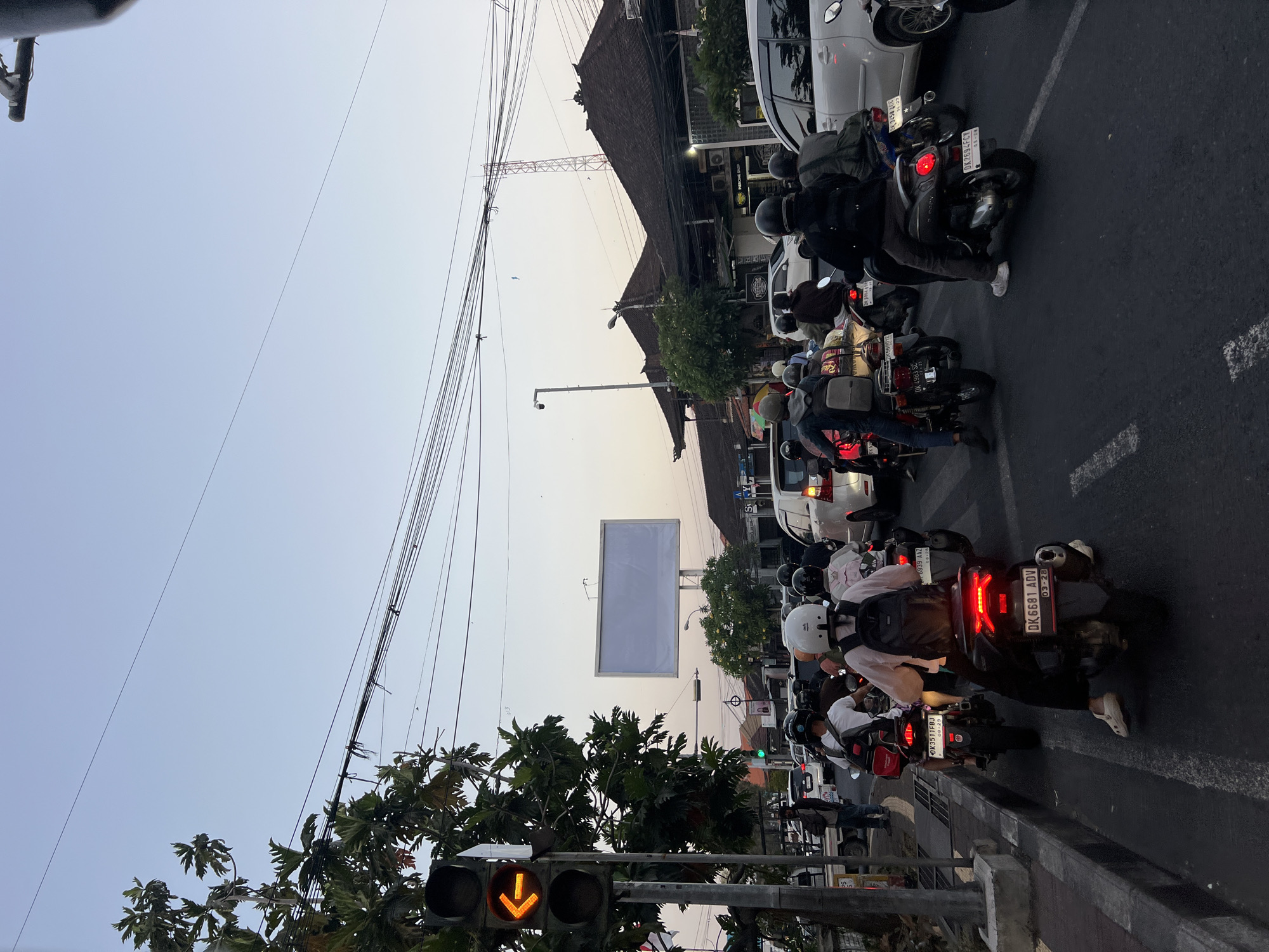 Rush hour motorbikes at a Denpasar intersection, dusk