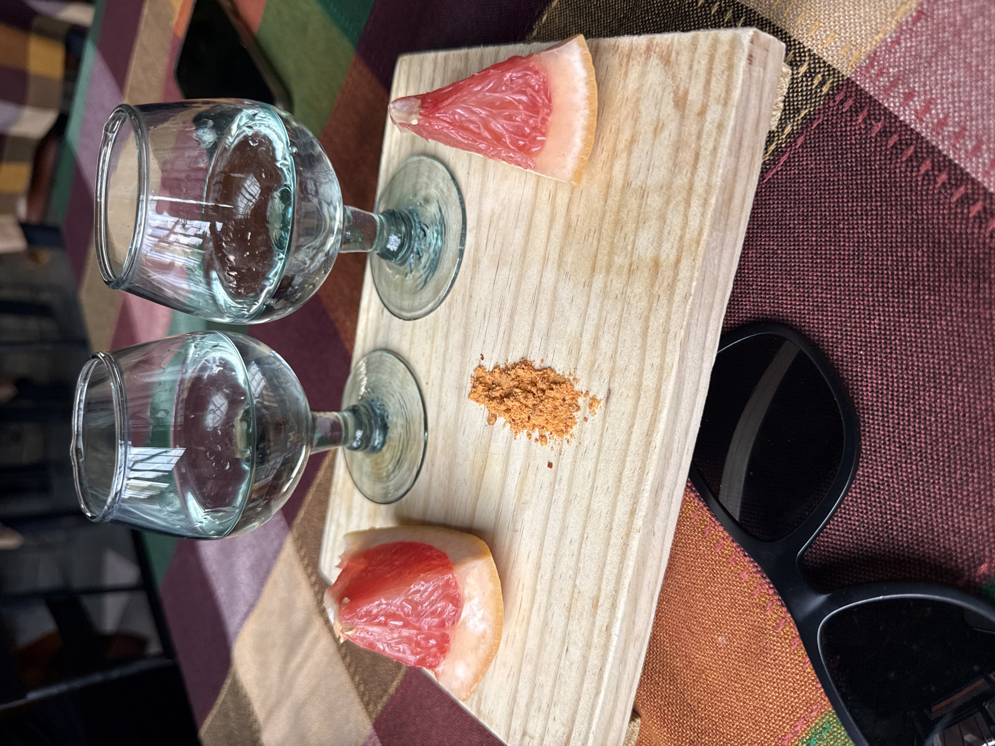 Wine glasses and grapefruit wedges arranged on wooden board