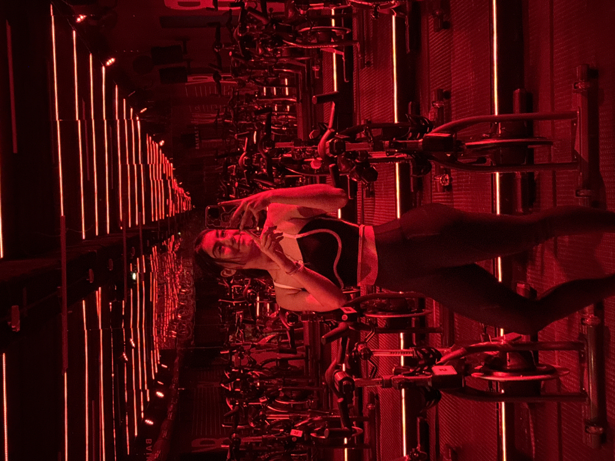 Woman photographed during cycling class in red-lit Puebla fitness studio