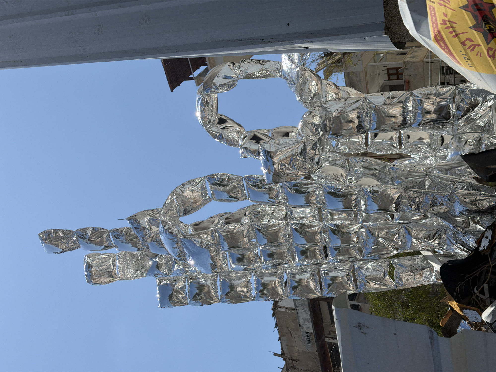 Reflective silver sculpture amid rubble on a Tel Aviv street