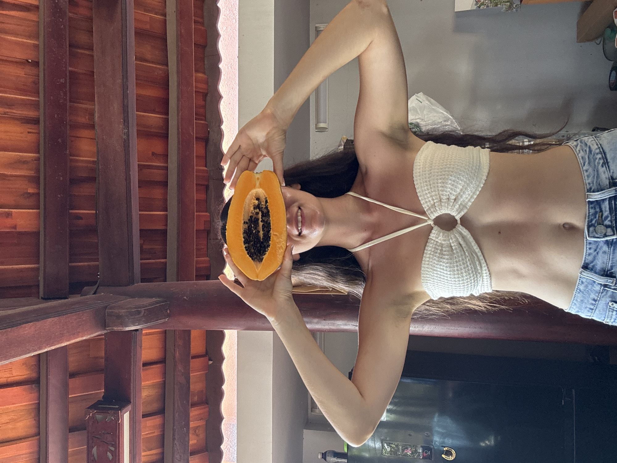 Woman poses with fresh papaya indoors in Mũi Né