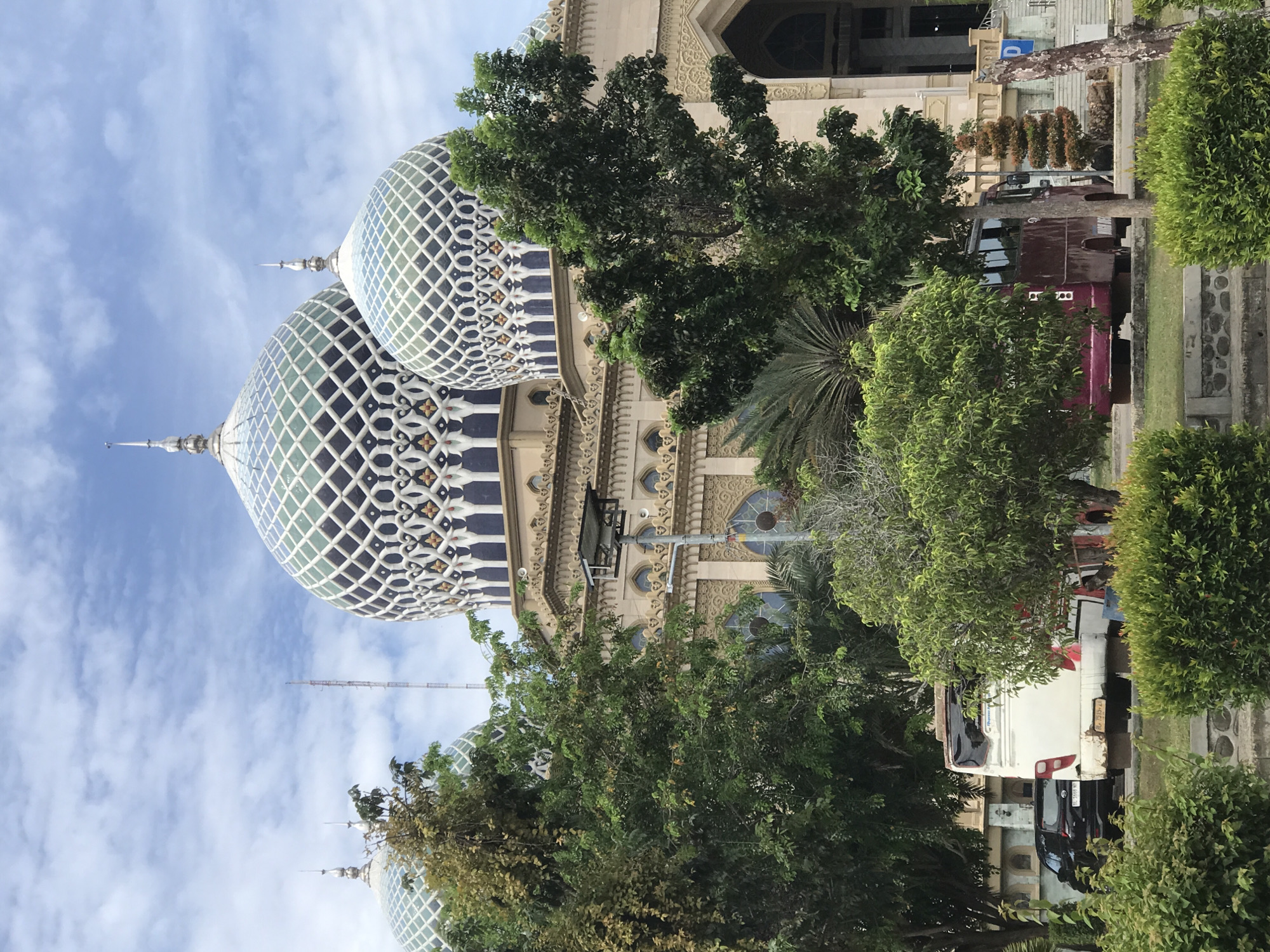 Mosque with twin domed architecture observed under partly cloudy skies