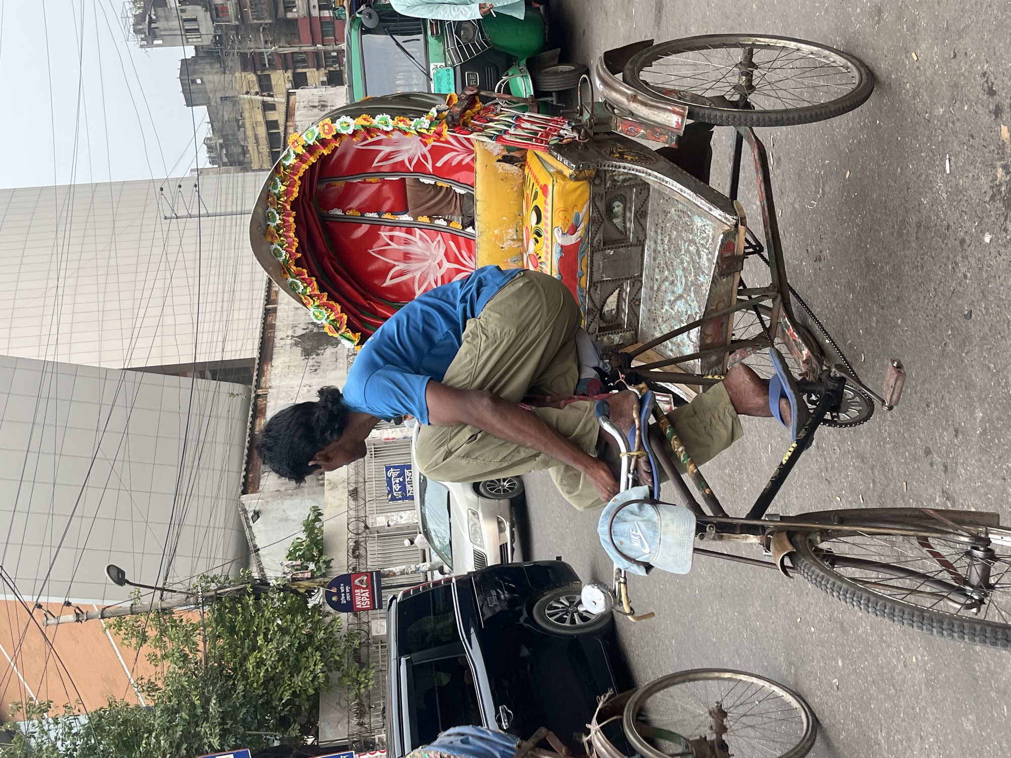 Decorated rickshaw navigates busy Dhaka streets amid typical urban activity