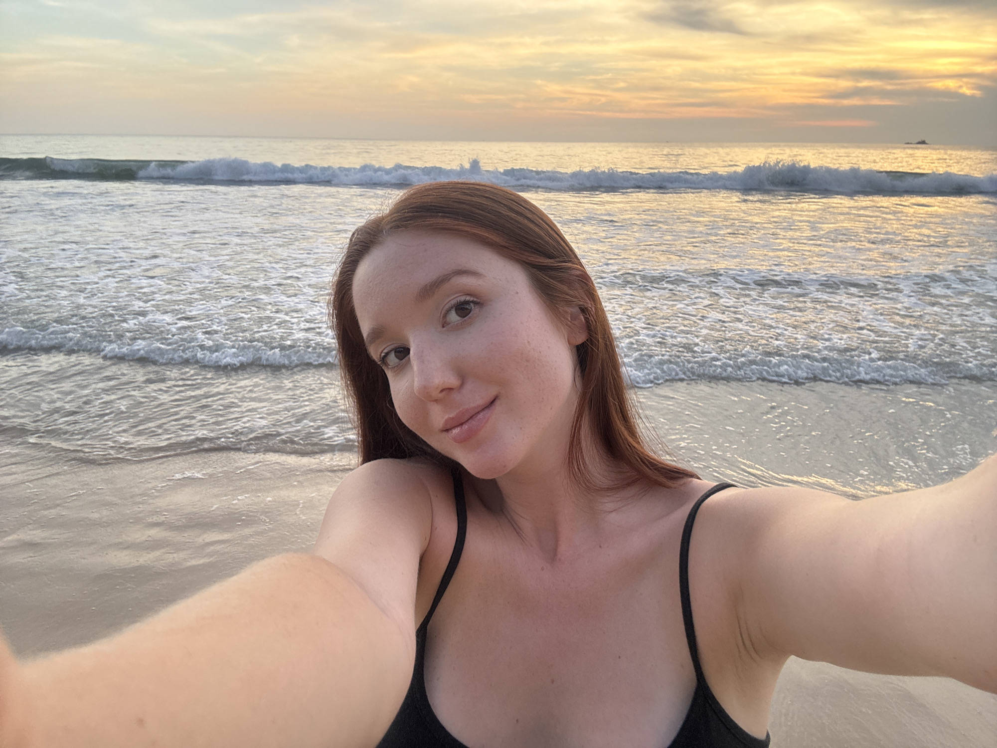 Woman captures sunset selfie on Bang Tao Beach, Thailand