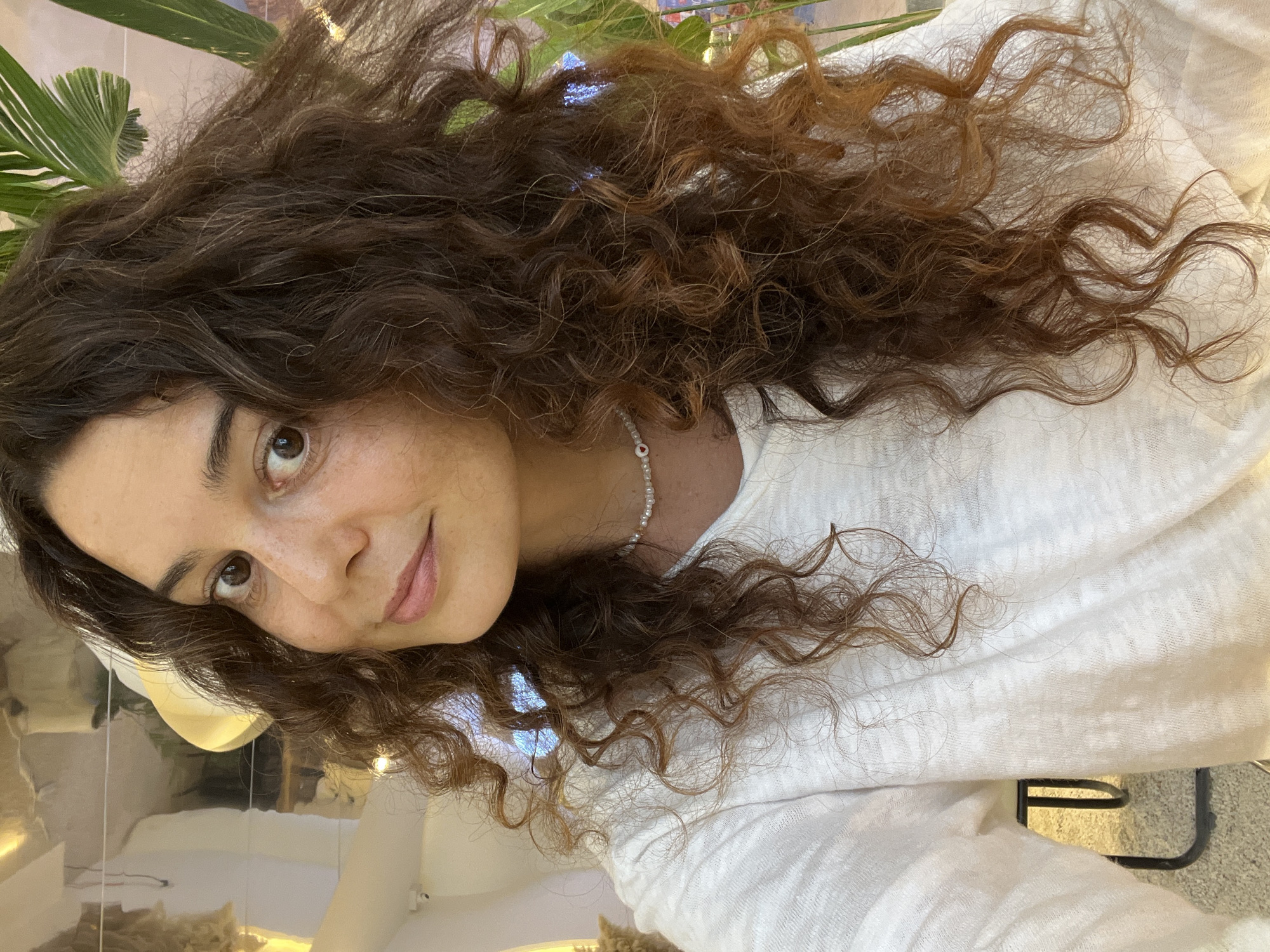 Overhead close-up, white tee and pearl necklace with heart pendant.