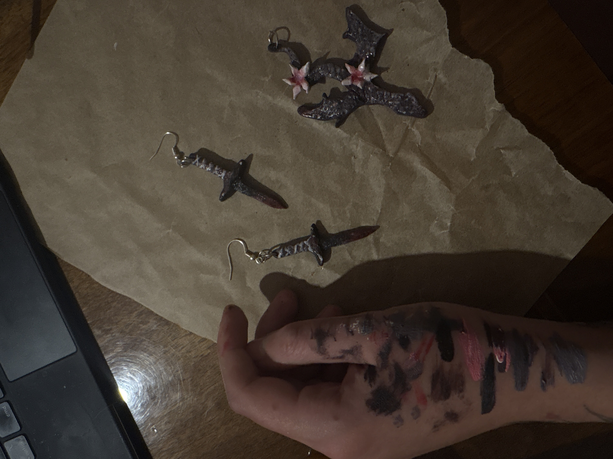 Person arranges dark jewelry pieces on paper in Yerevan