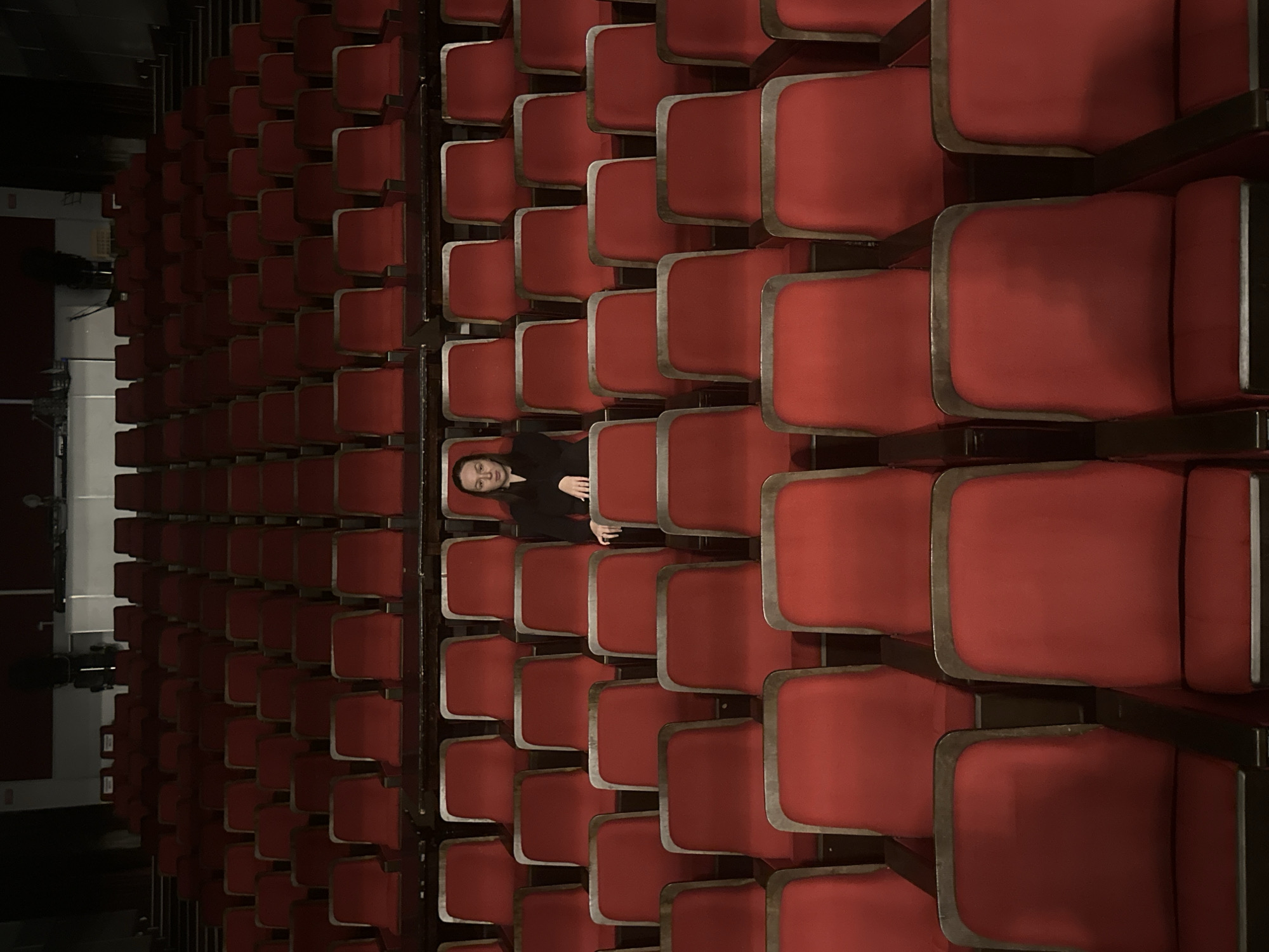 Empty red theater seats fill dimly lit auditorium