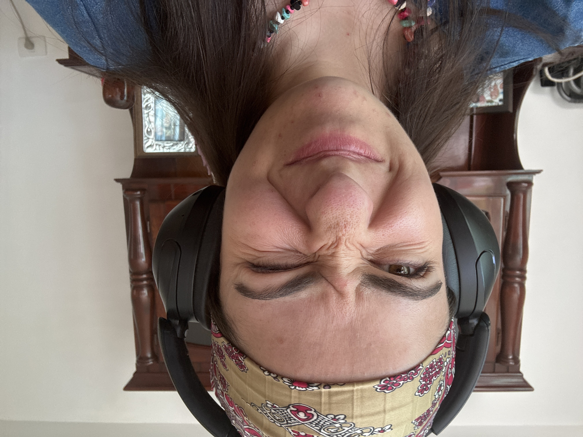 Woman in headphones squints indoors in Puebla home