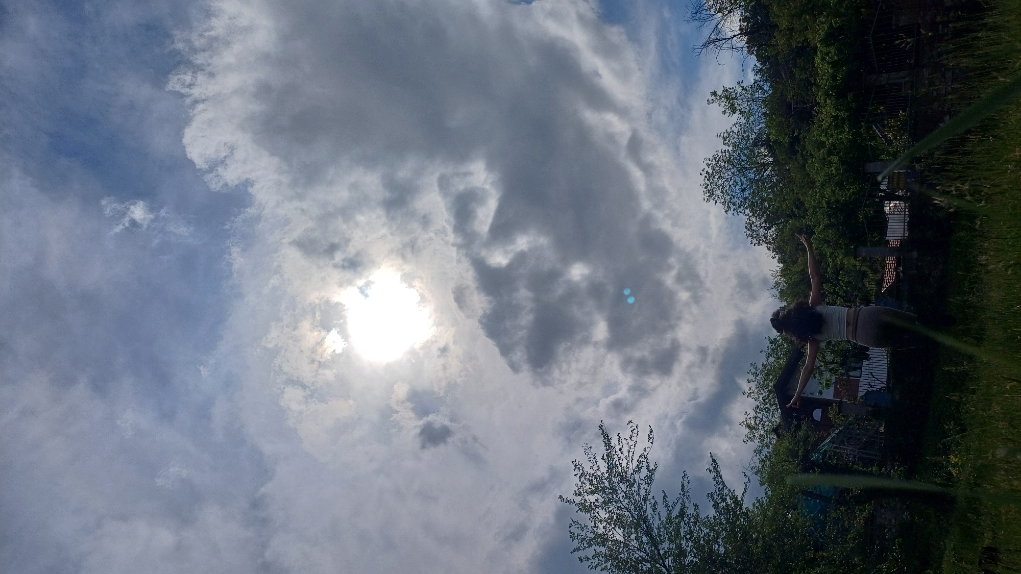 Person stands arms outstretched in Bulgarian field under cloudy skies