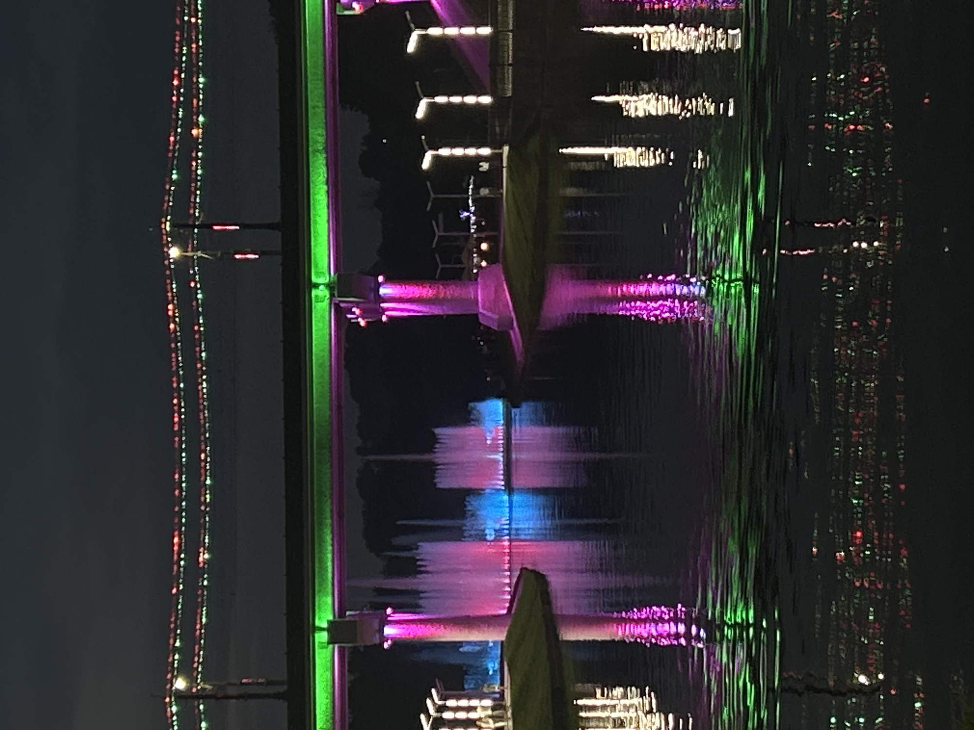 Bridge and fountains glow in purple and green at night