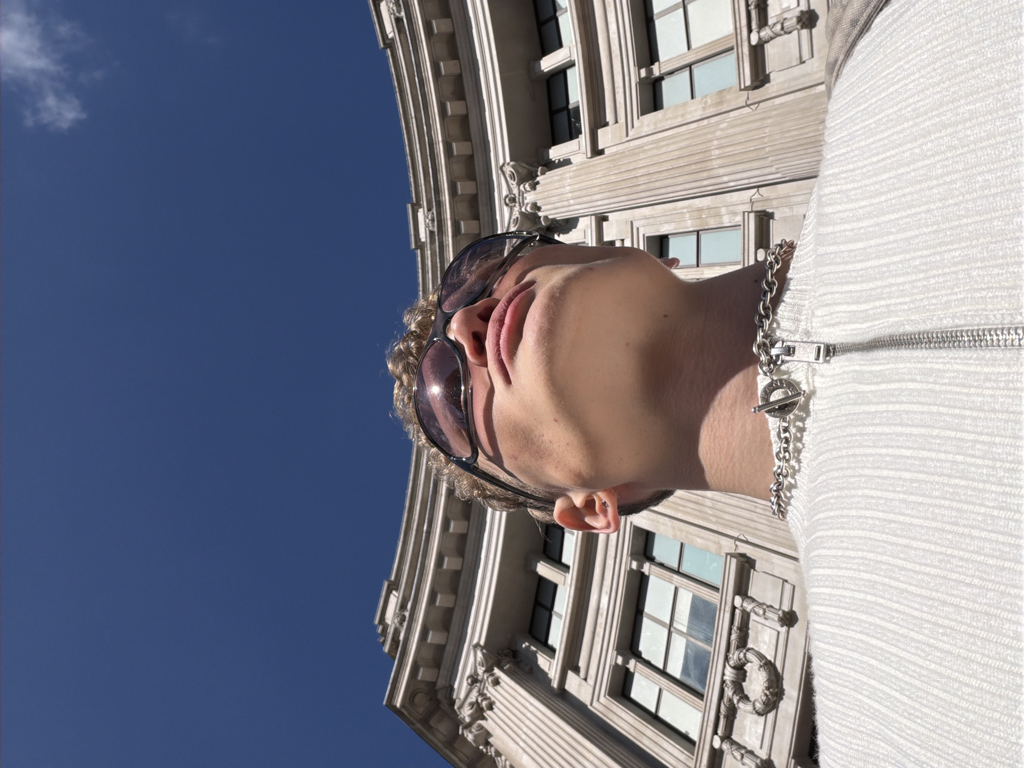Person in sunglasses and white jacket photographed in London