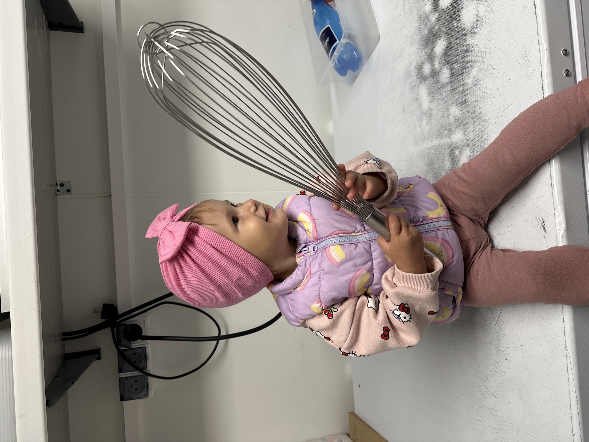 Toddler in pink hat plays indoors in Wisła, Poland