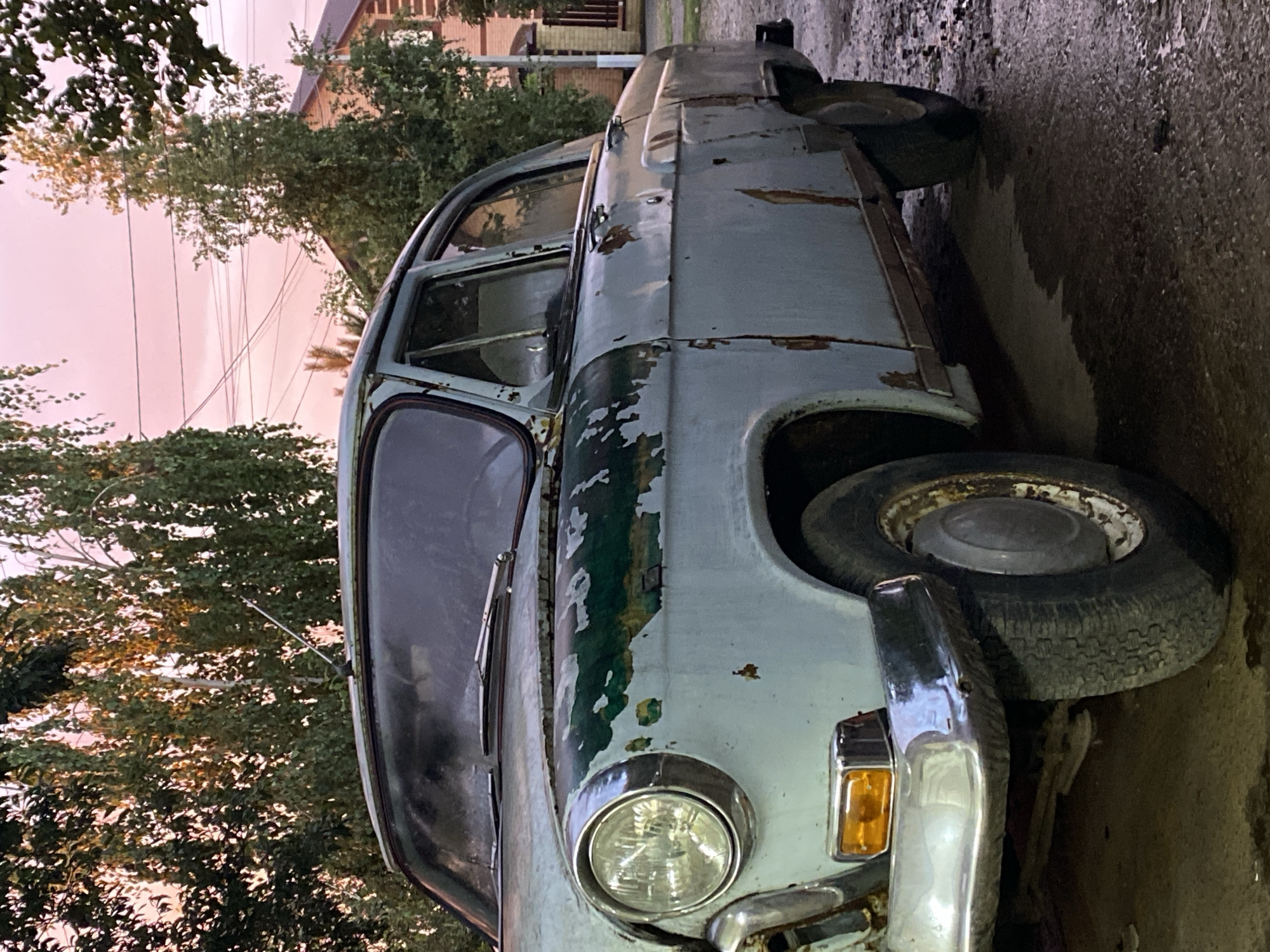 Rusted blue sedan parked on wet asphalt in Dinskaya