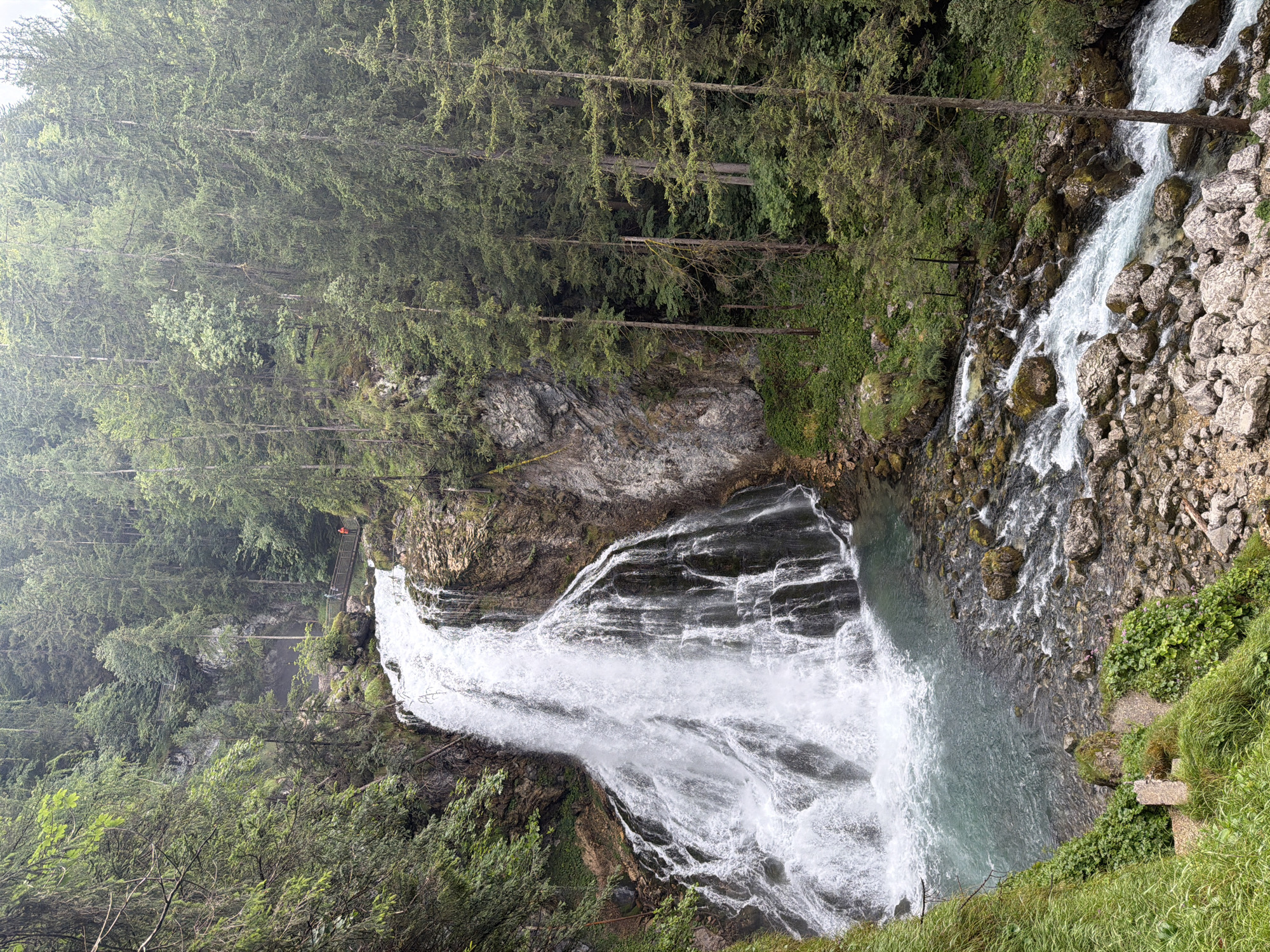 Powerful waterfall cascades through forested alpine cliffs in Kellau