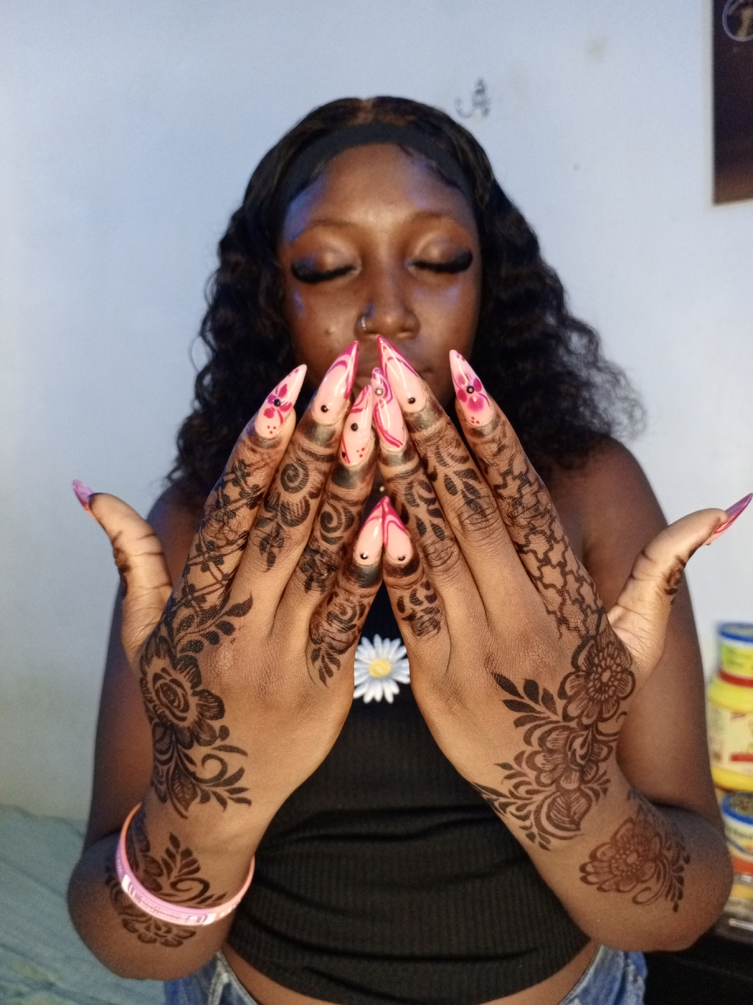 Woman showcases henna tattoos and pink nail art indoors