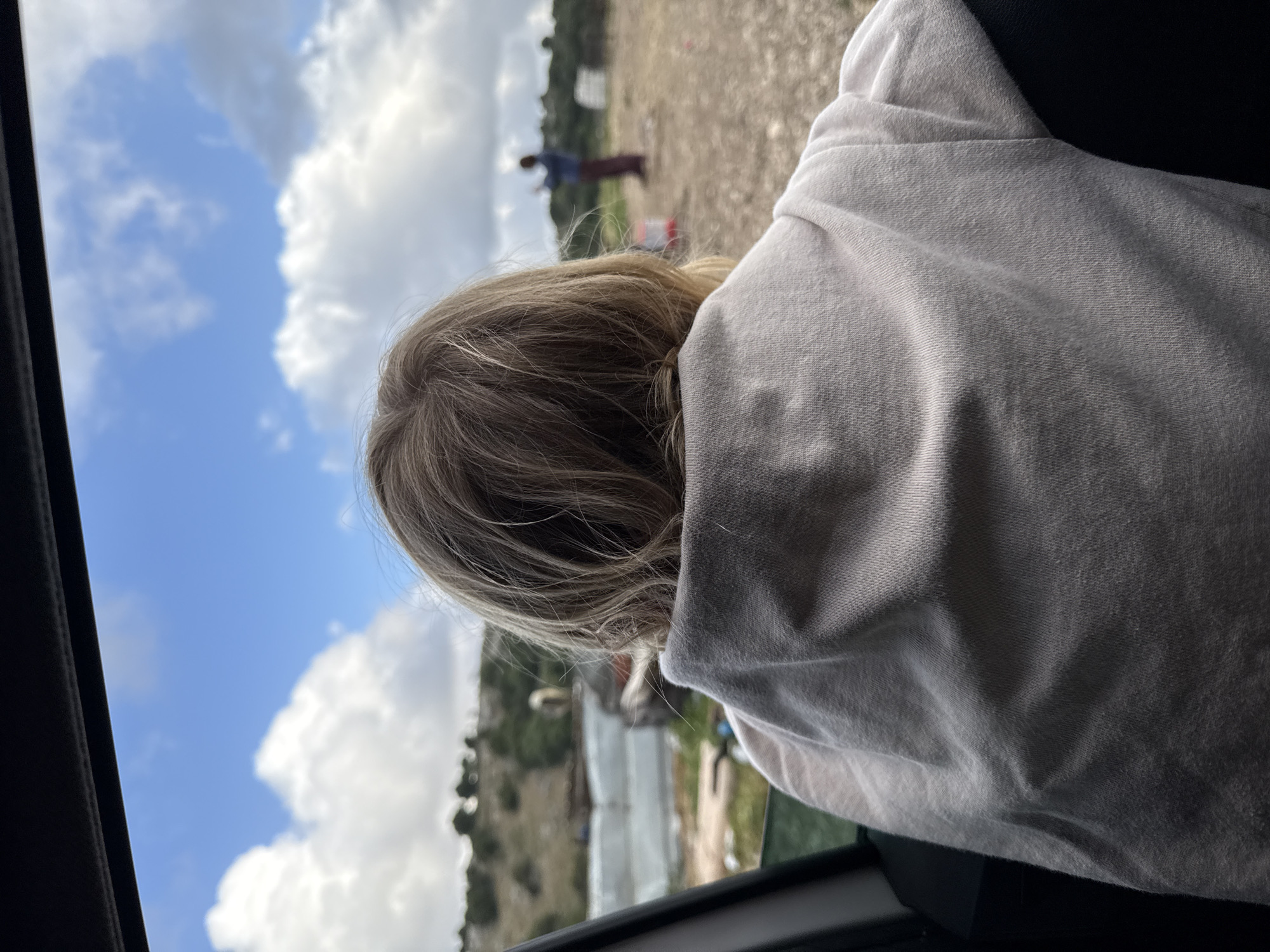 Passenger observes figure in field from car window in Hila