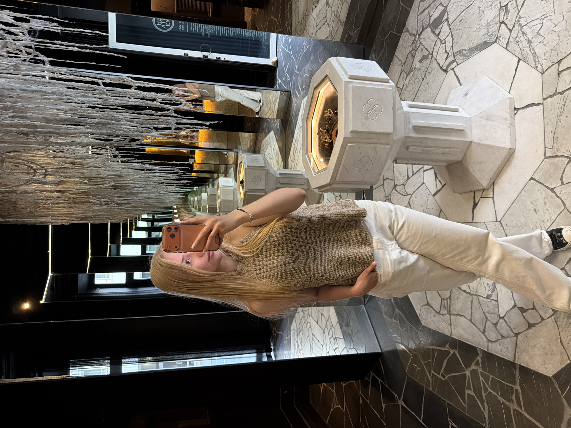 Woman takes mirror selfie in sophisticated mirrored interior space