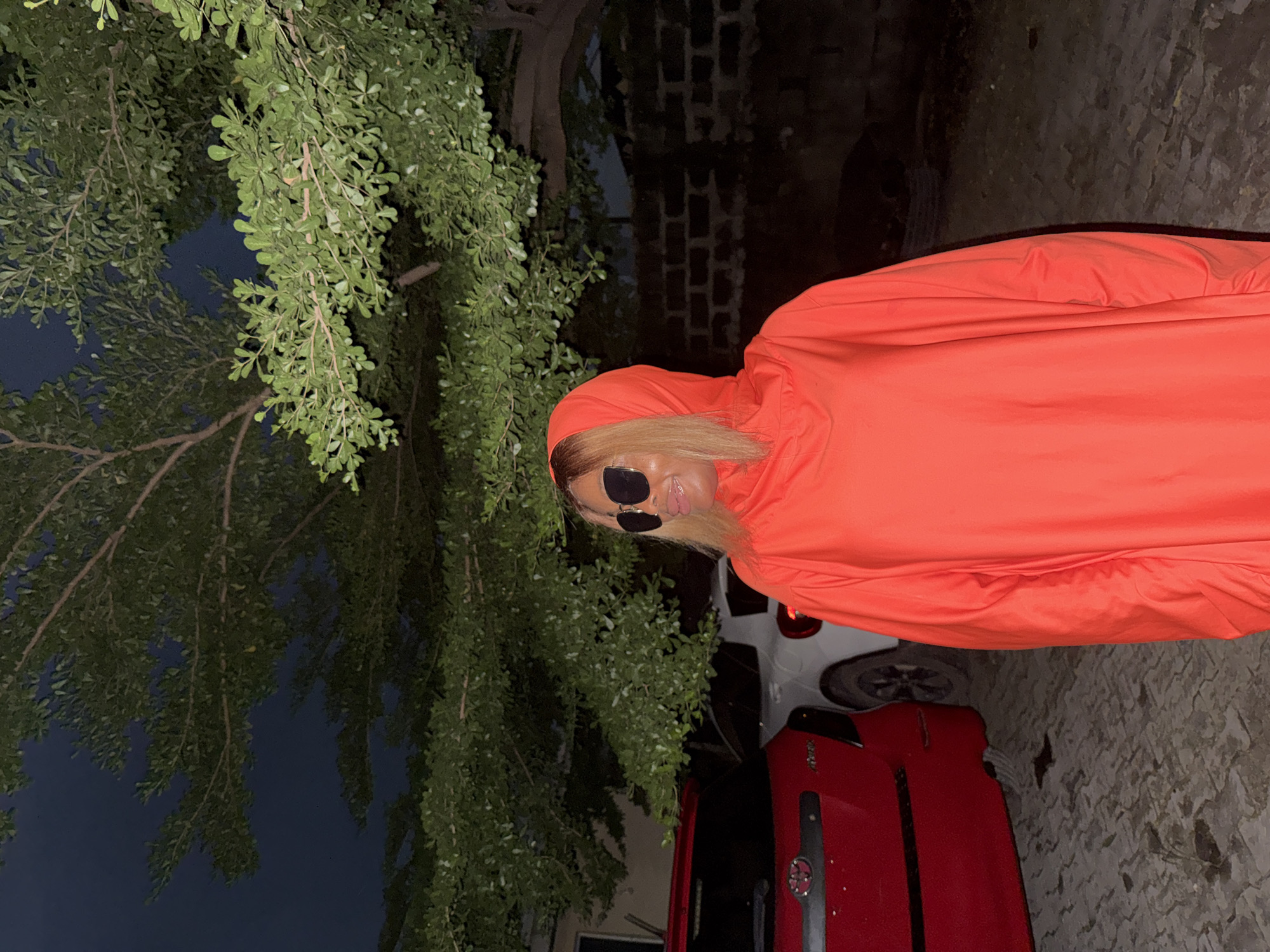 Night poses in orange near parked cars, Ado Nigeria