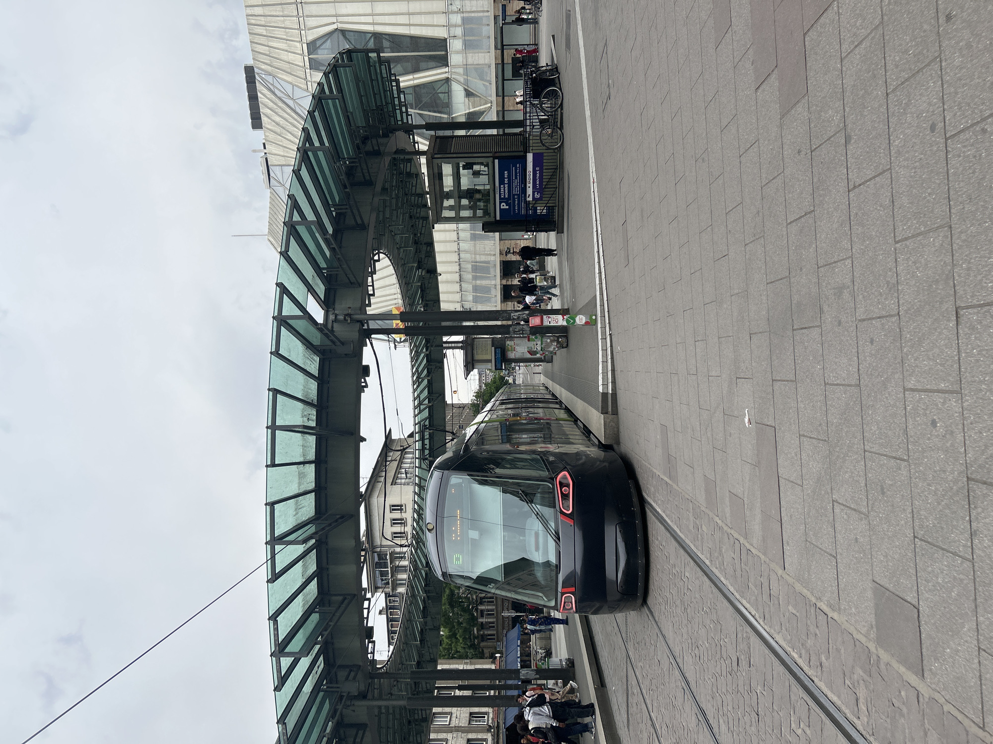 Black tram stops at covered station in Strasbourg