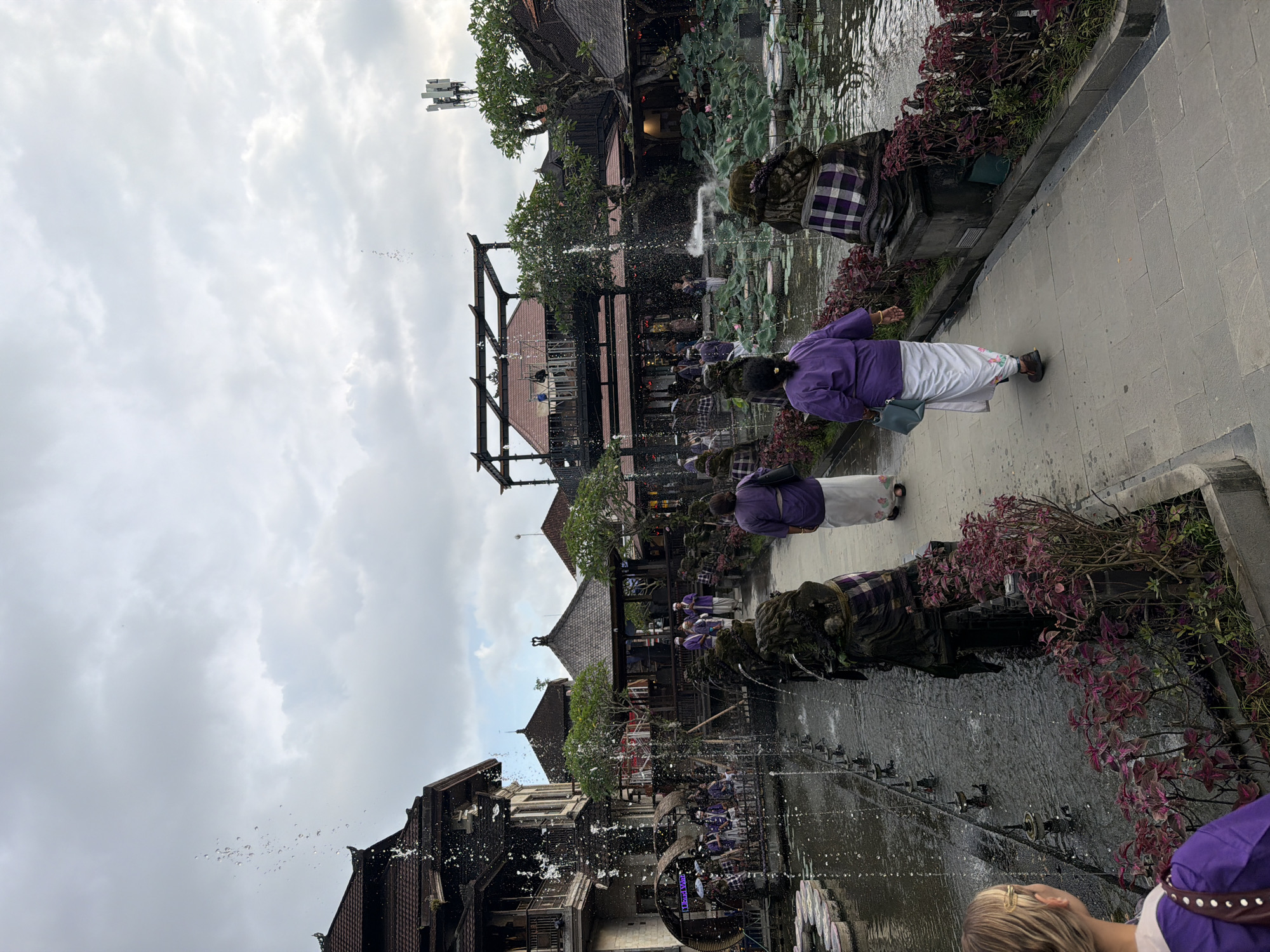 Tourist documents Ubud temple tour featuring lotus ponds, statues
