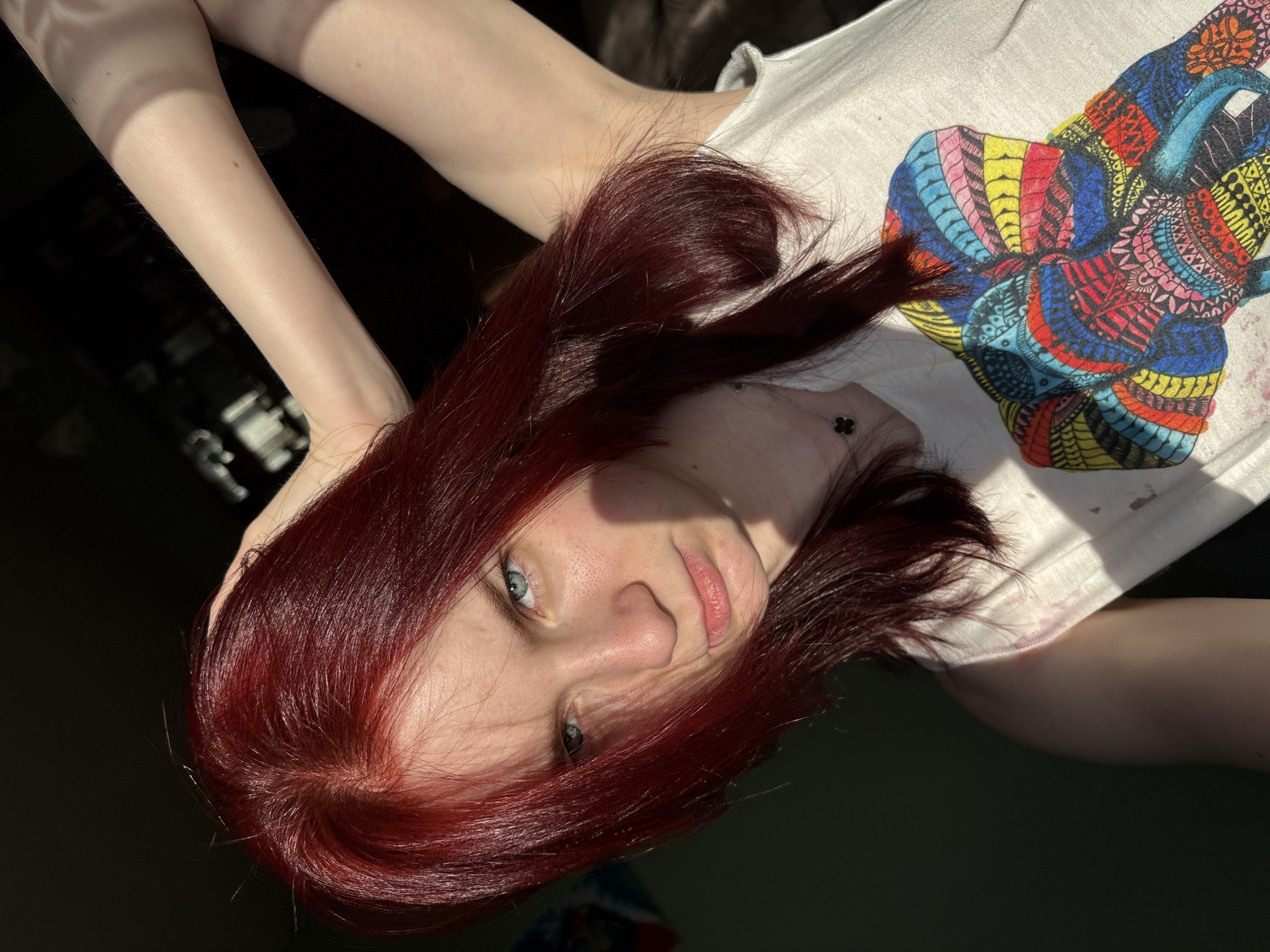 Red-haired woman photographed in bedroom wearing Thailand t-shirt