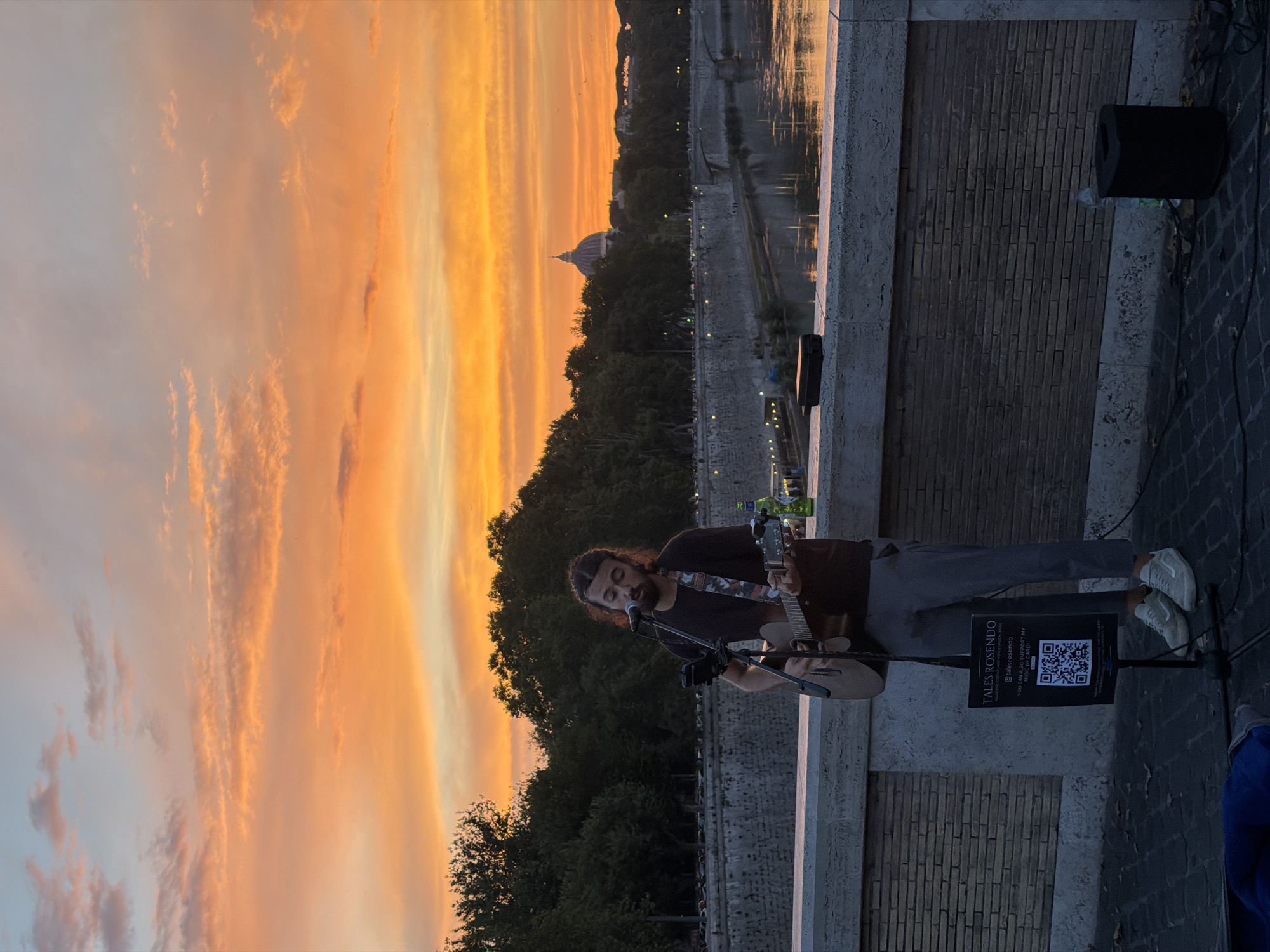 Acoustic busker performs on a bridge at golden hour