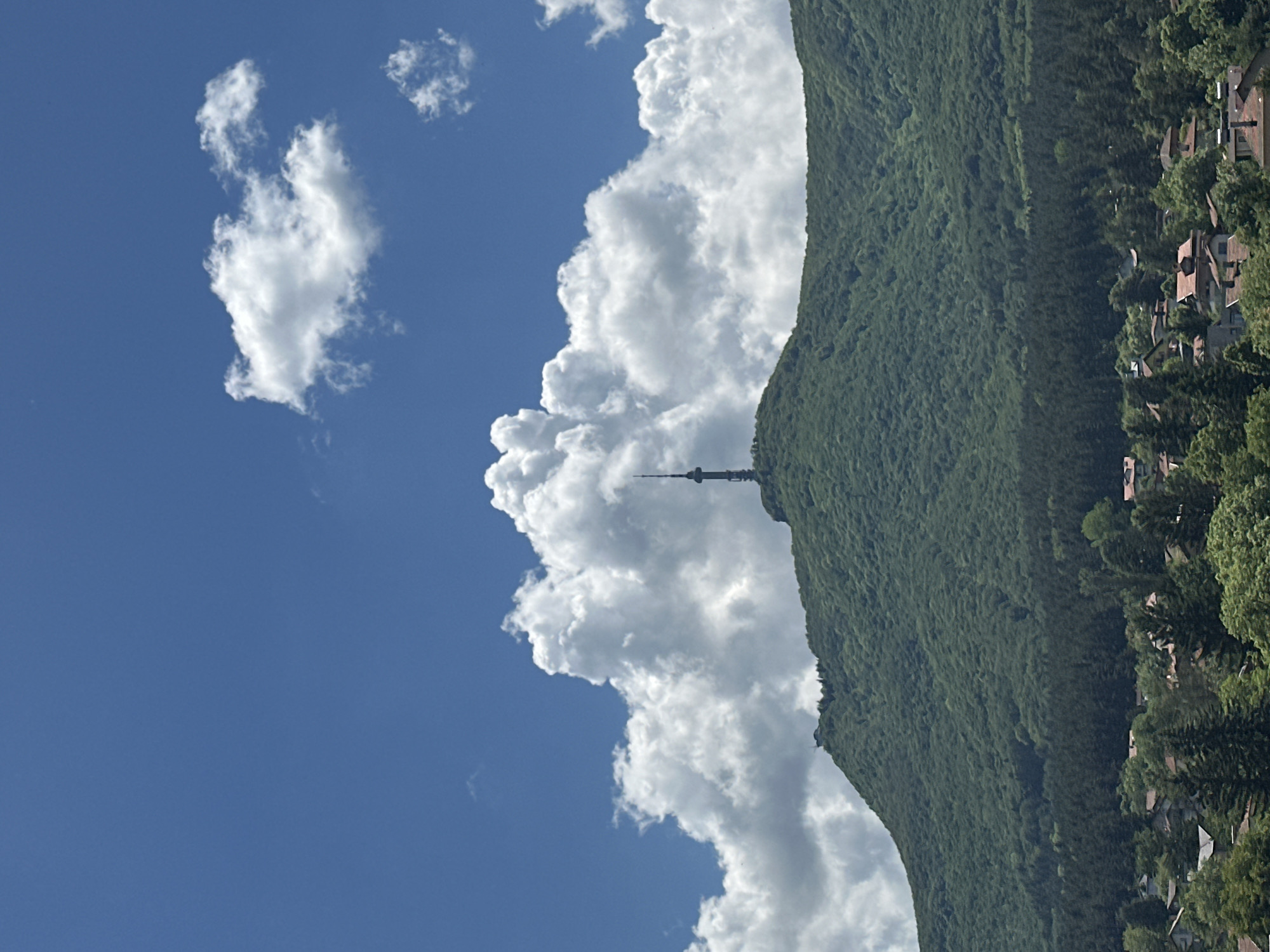 Communication tower observed on verdant mountainside under cloudy skies