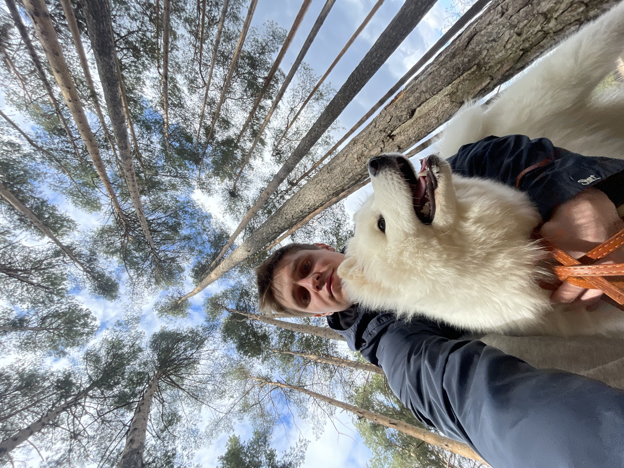 Person and white dog photographed in forest near water