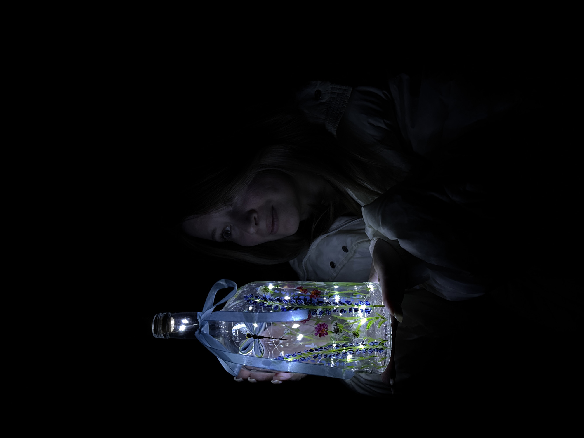 Woman poses with illuminated decorative bottle in Russian village
