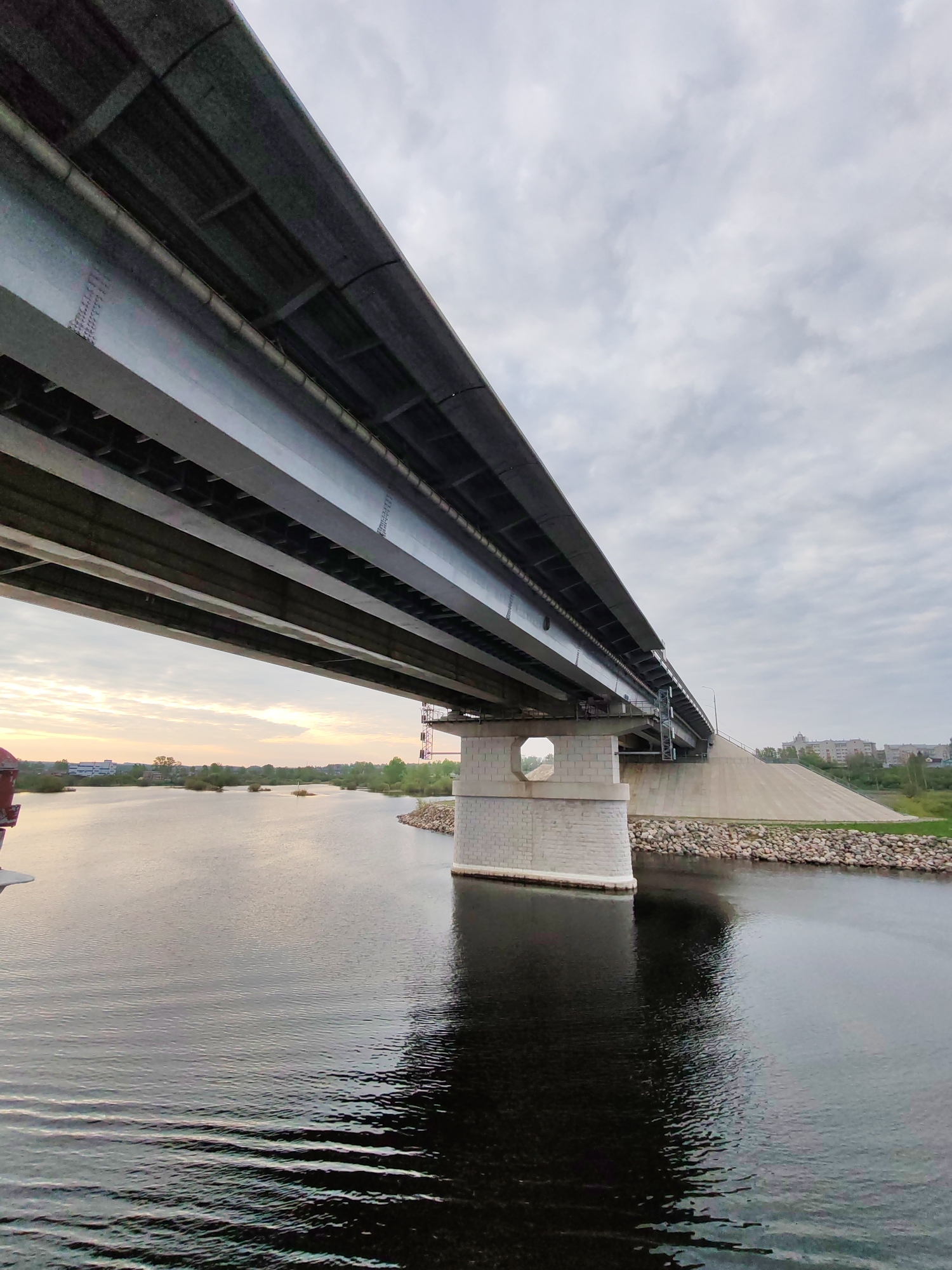 Barge passes under bridge on Sheksna River at sunset