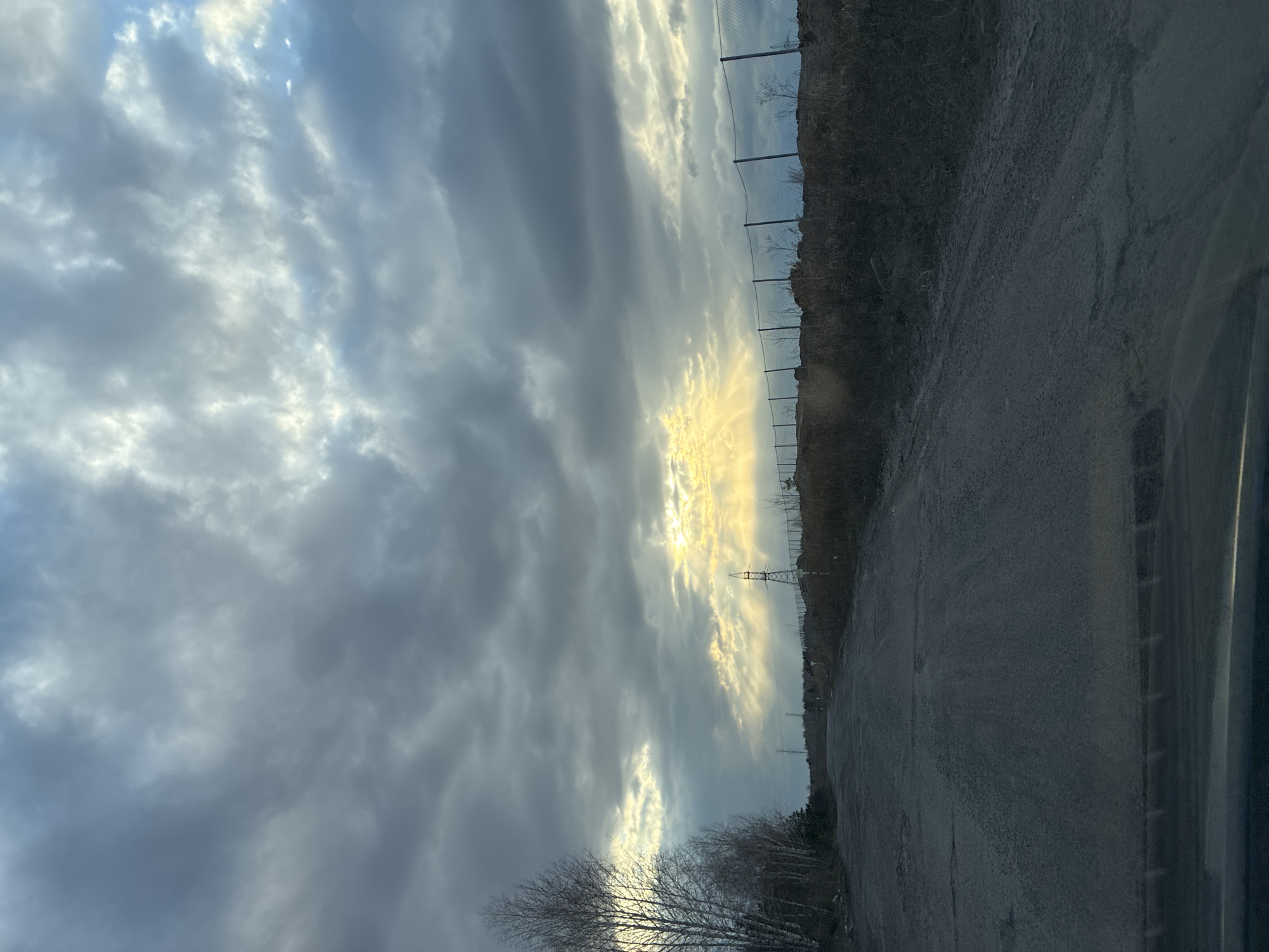 Sunlight breaks through clouds above roadside landscape