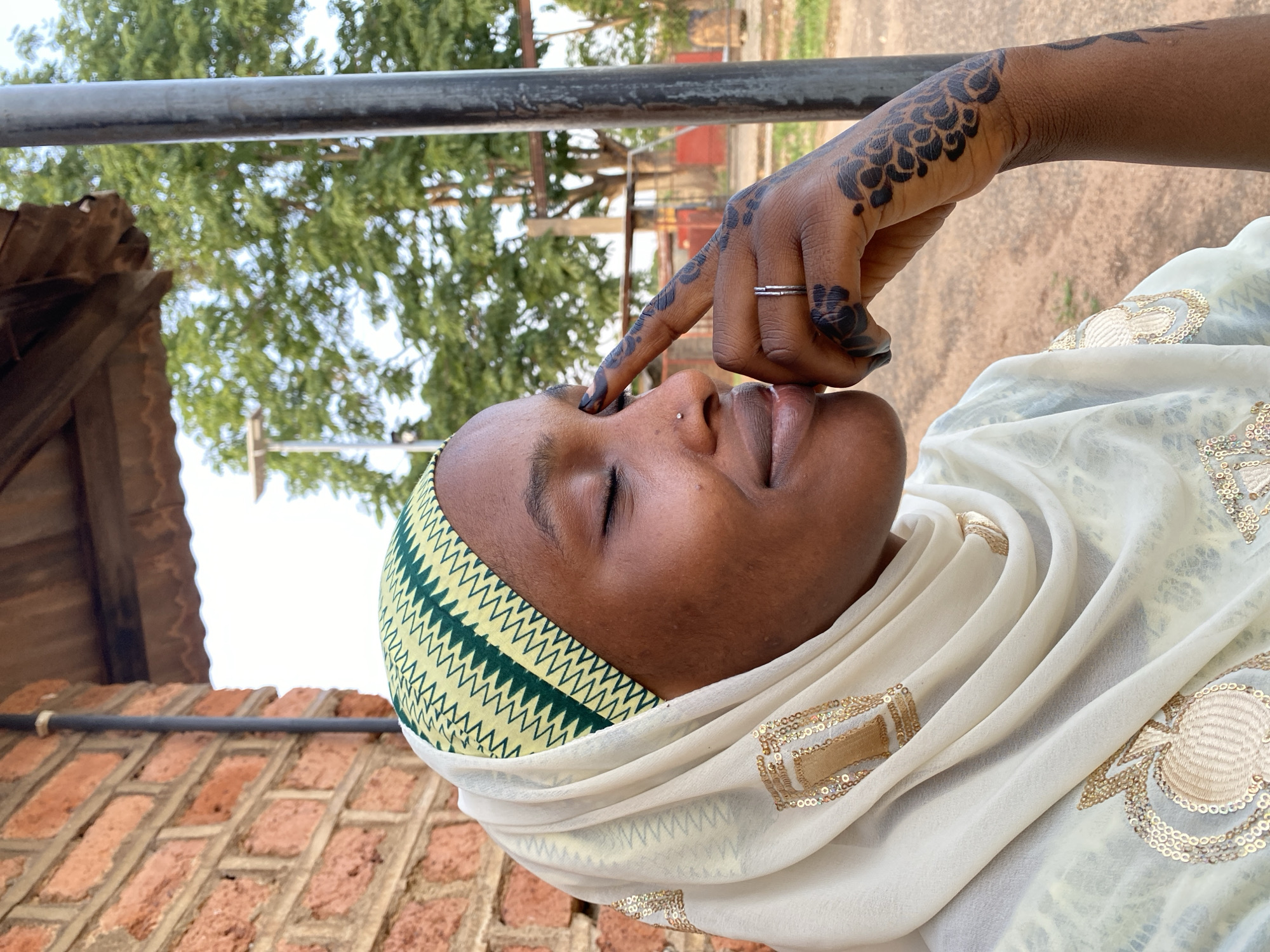 Woman in traditional dress photographed near brick building in Vom