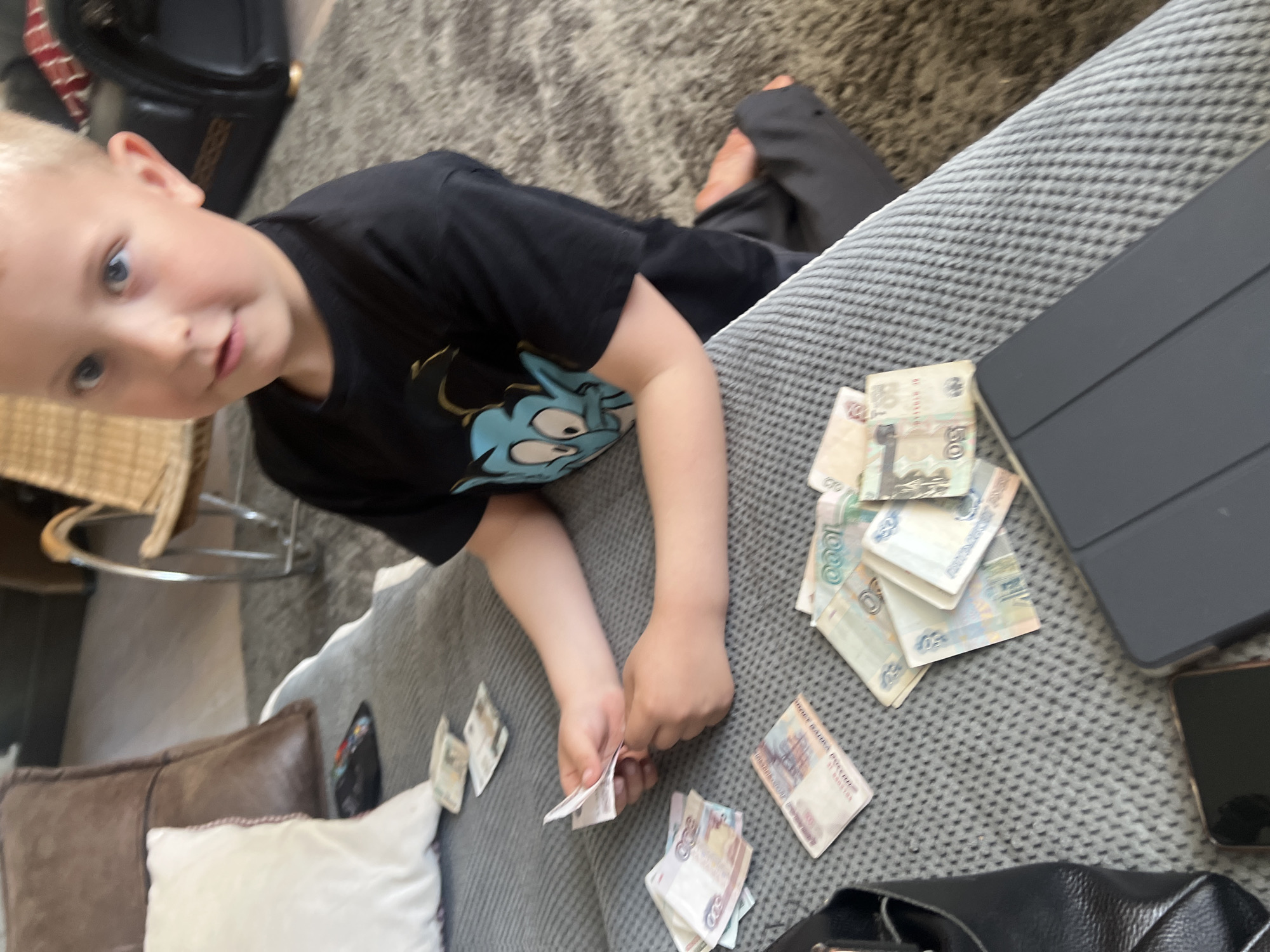 Child counts Russian rubles on sofa during domestic scene