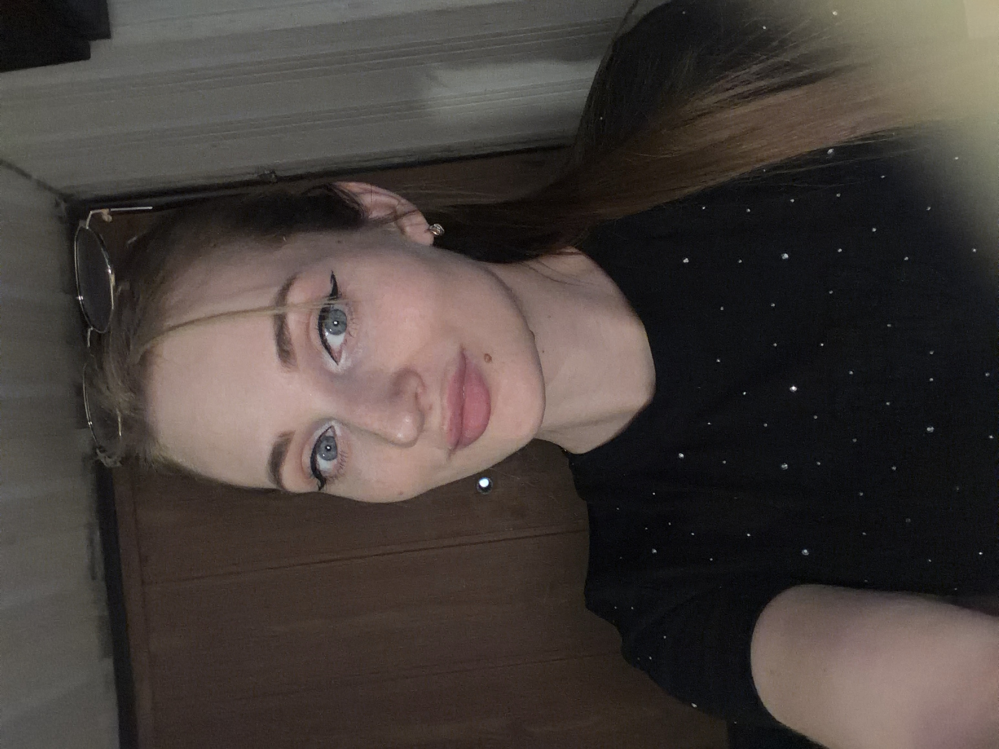 Selfie portrait with winged eyeliner and a sparkly black top.