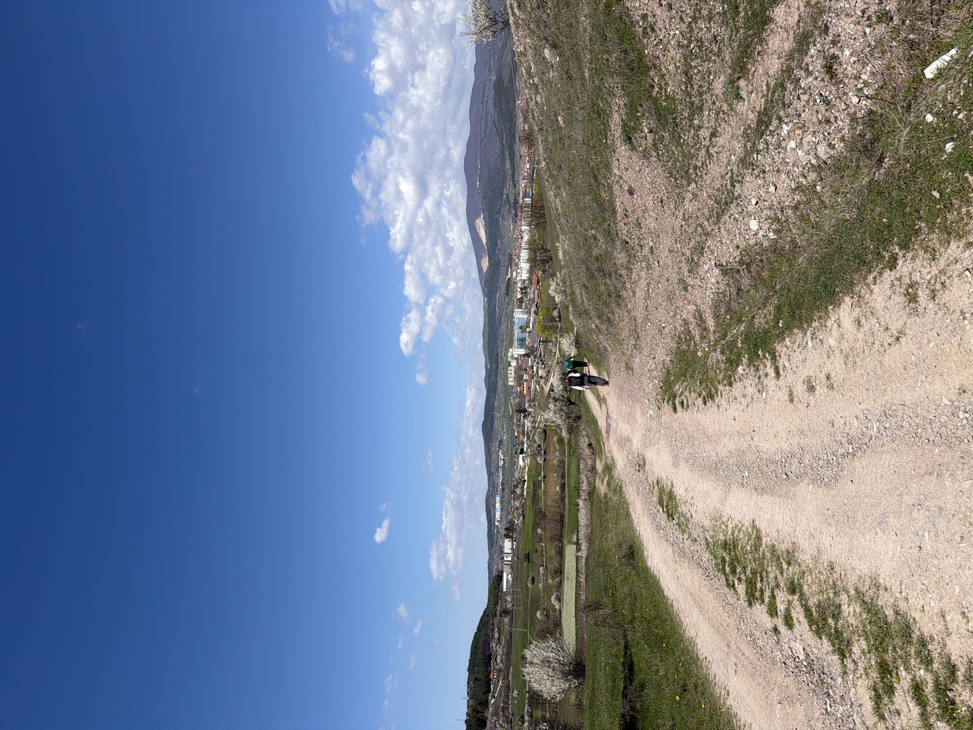 People walk dirt road near Panagyurishte on sunny spring morning