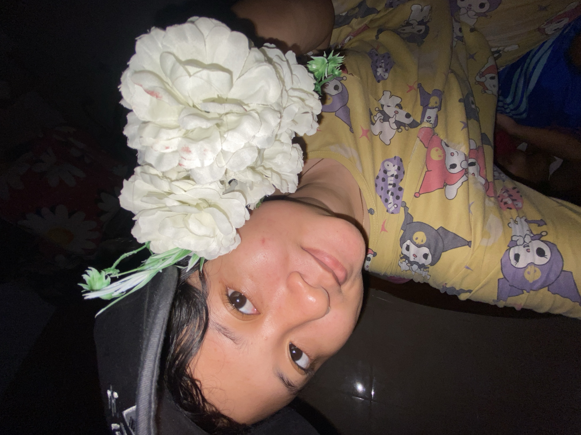 Person with flower-decorated cap holds bouquet in Gelam