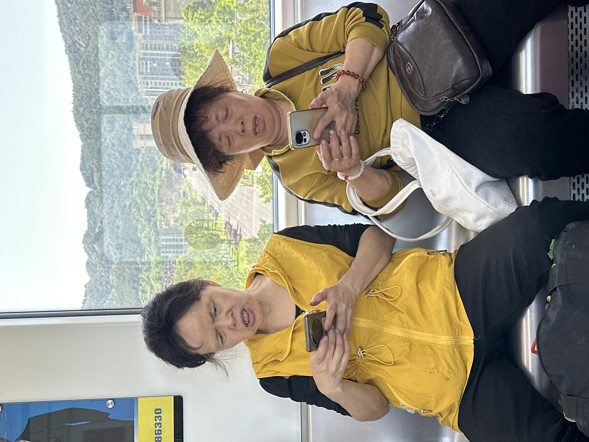 Two women use phones on public transport in Shuangfu